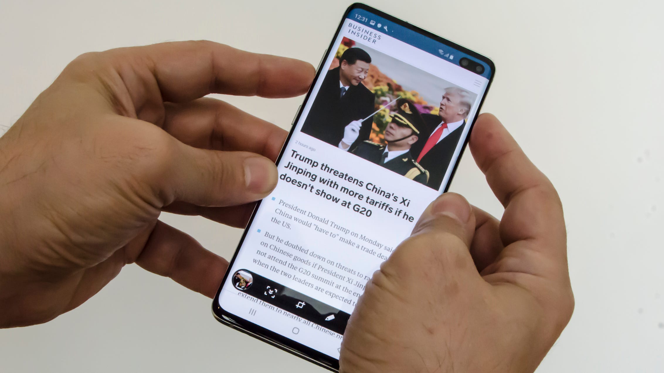 A man holding a Samsung Galaxy S10 and pressing the buttons on the side.