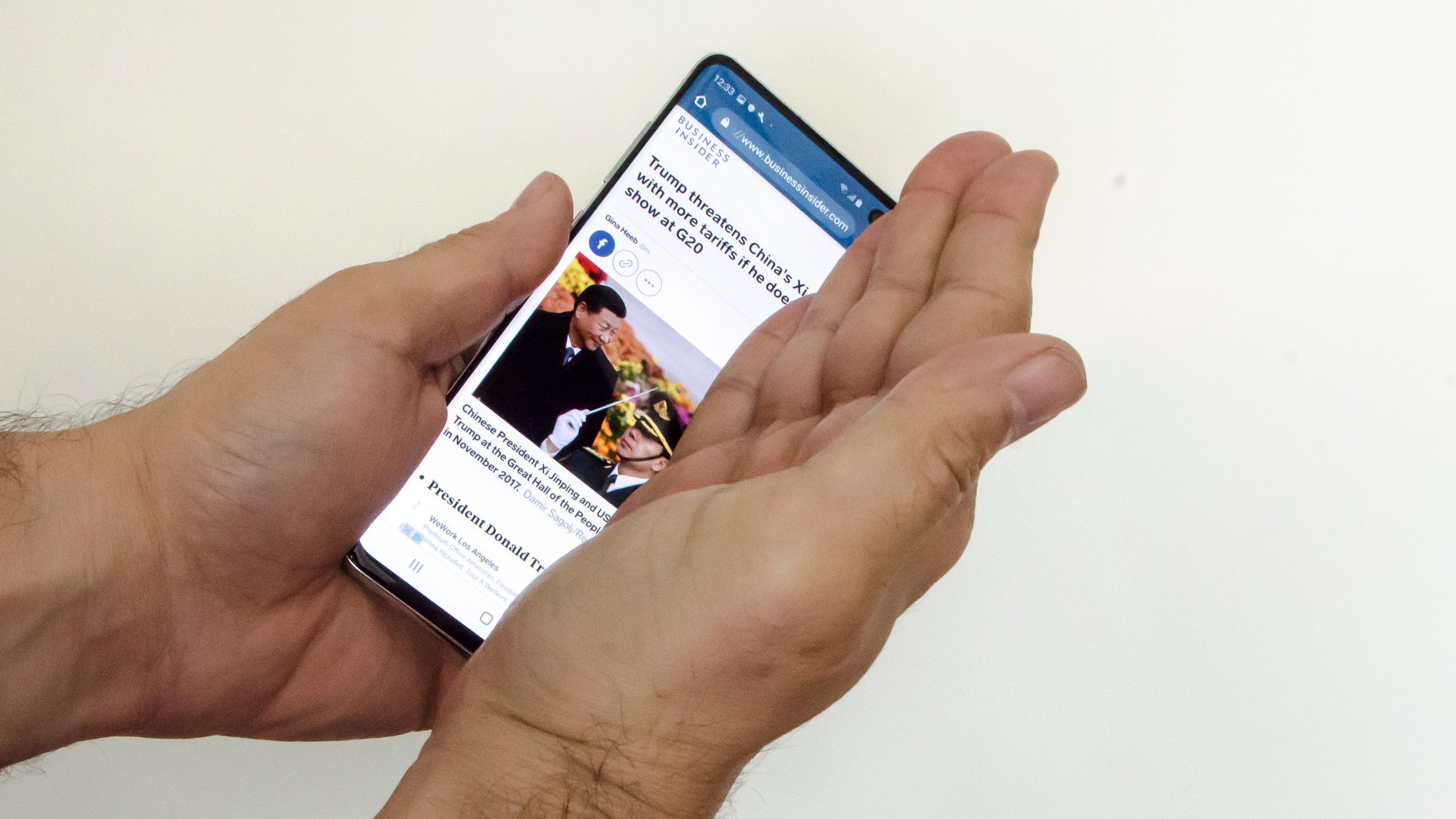 A man laying the side of his hand across a Samsung Galaxy S10's screen.