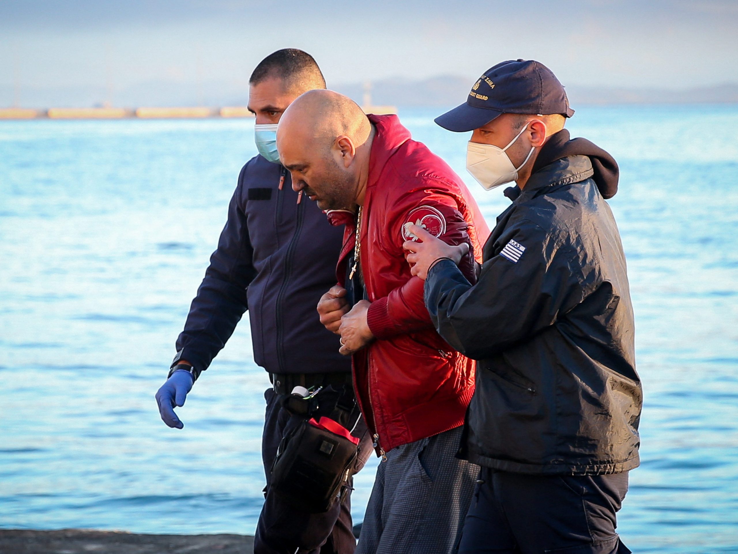 A passenger from the Italian-flagged Euroferry Olympia the being helped by members of the Greek coast guard