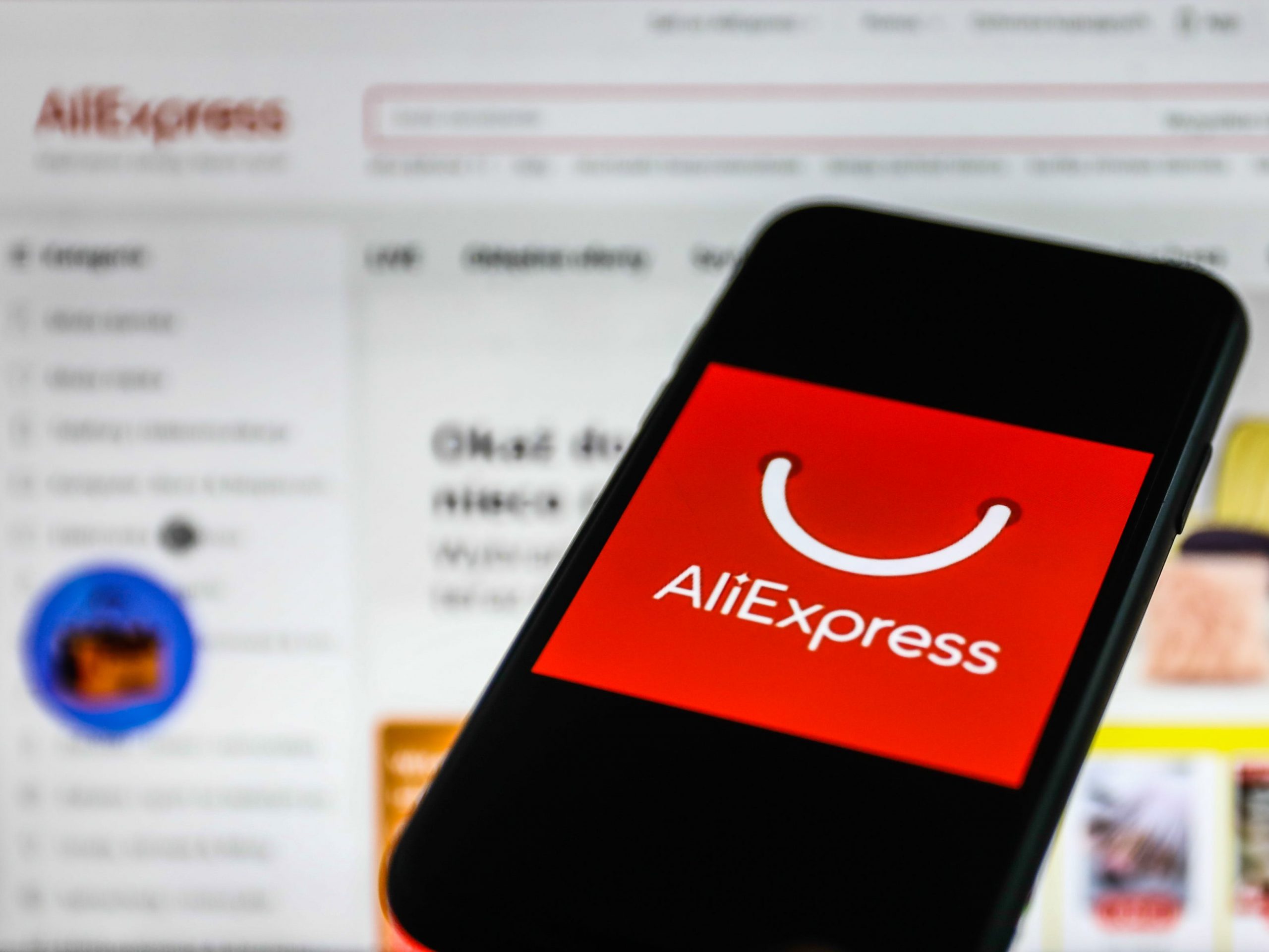 AliExpress logo displayed on a phone screen and AliExpress website displayed on a laptop screen. Photo taken in January 2022.