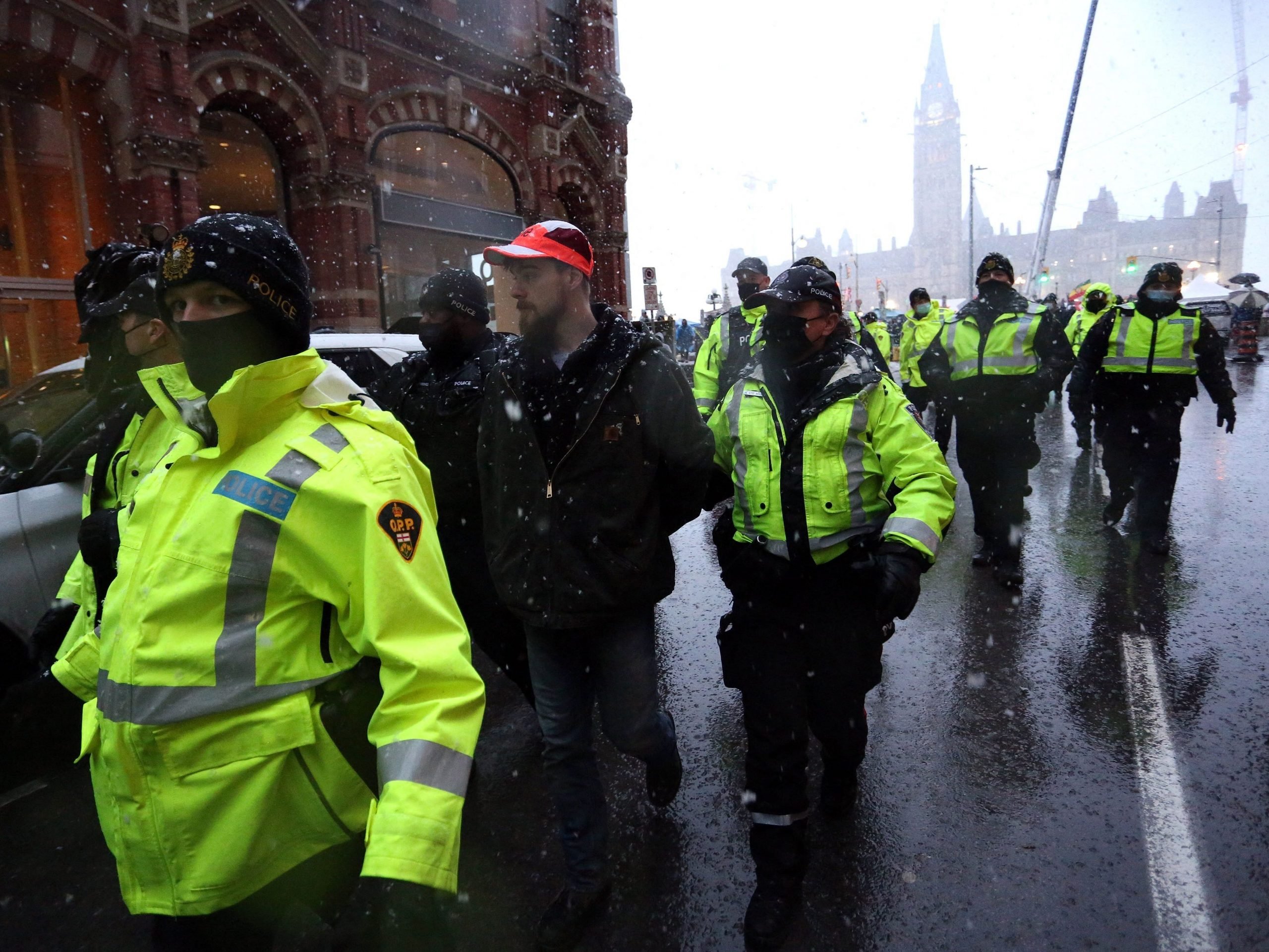 Police officers escort an arrested protester to a police car during a protest over pandemic health rules and the Trudeau government in Ottawa, Canada on February 17, 2022.