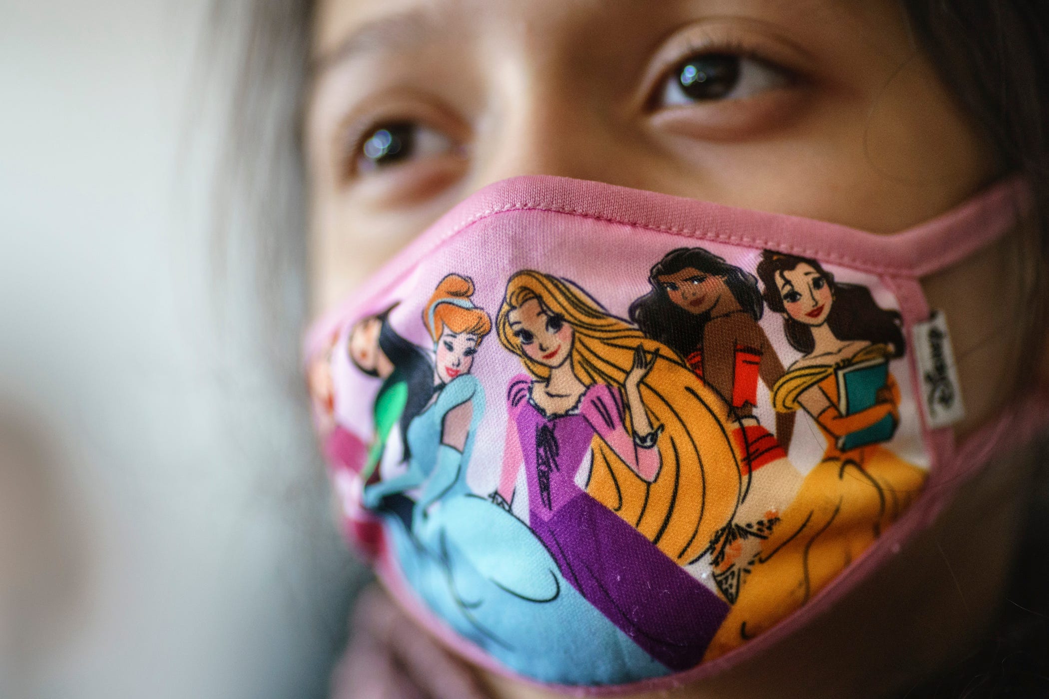 A student wears a mask with Disney characters on it.