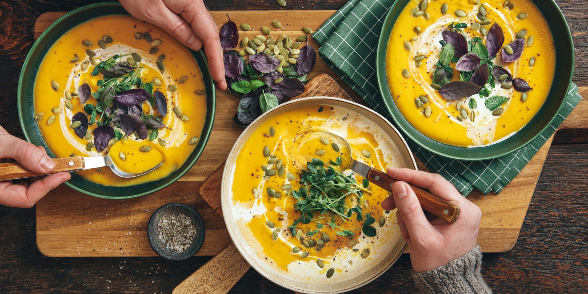 Overhead shot of three soup bowls with people going to take a spoonful