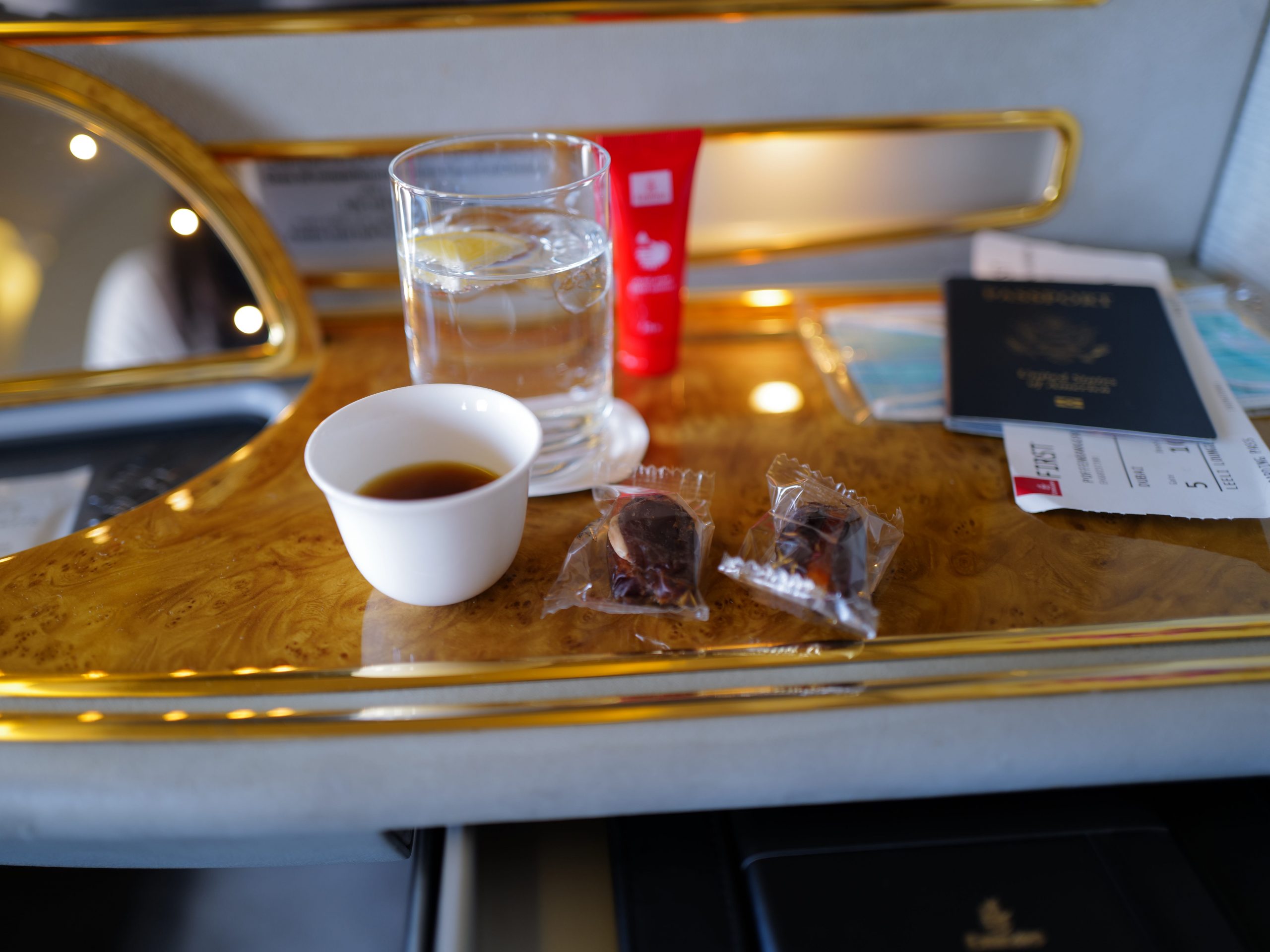 Glass of water, passport, and snacks on table in airplane seat