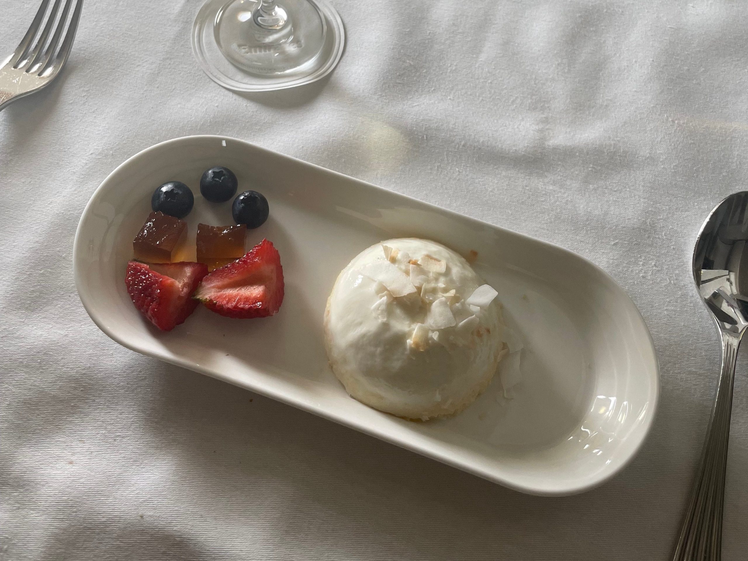 Stawberries, blueberries, and panna catta on a plate with glass of champagne