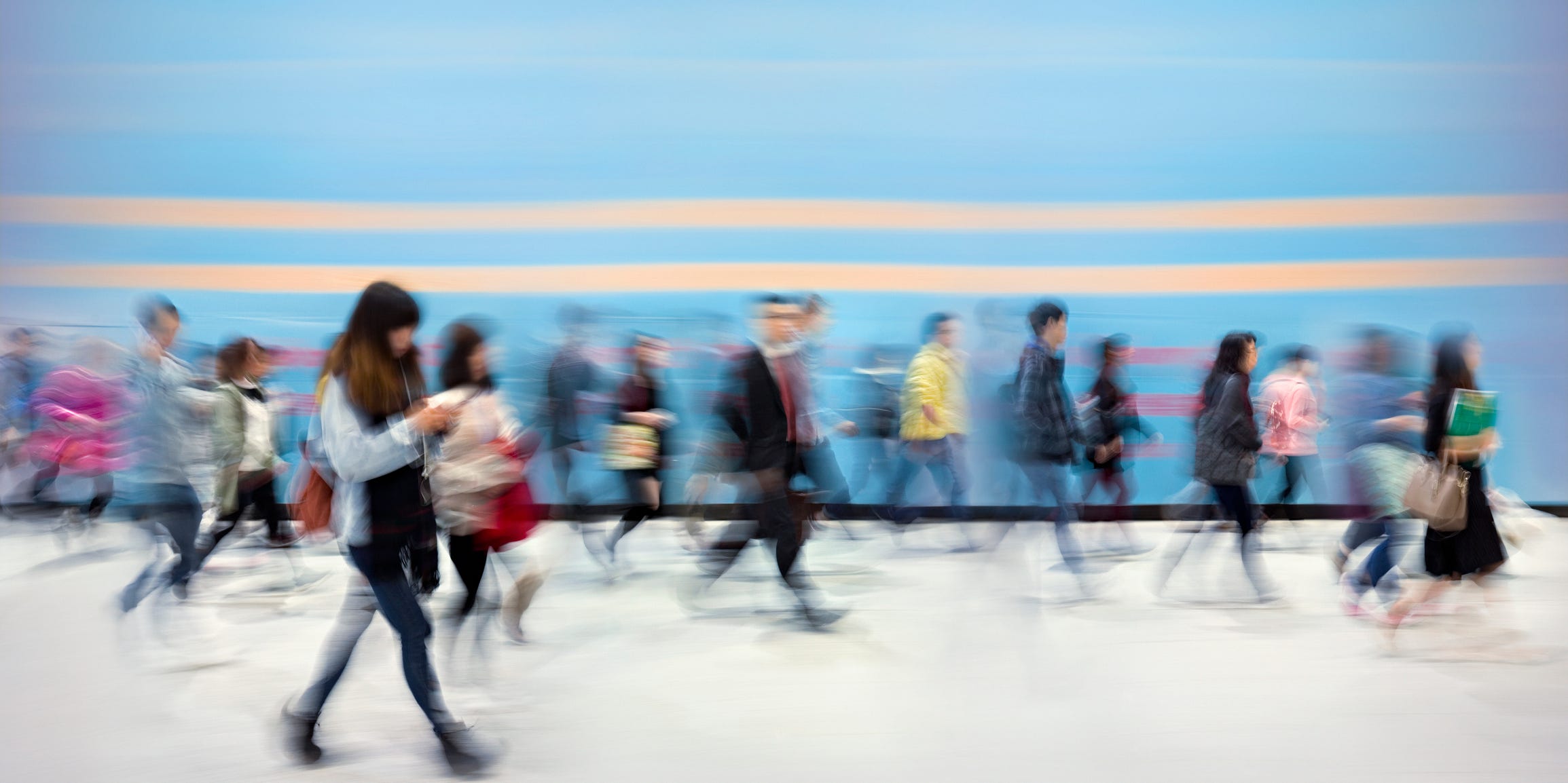 A blurred image of people walking across a sidewalk.