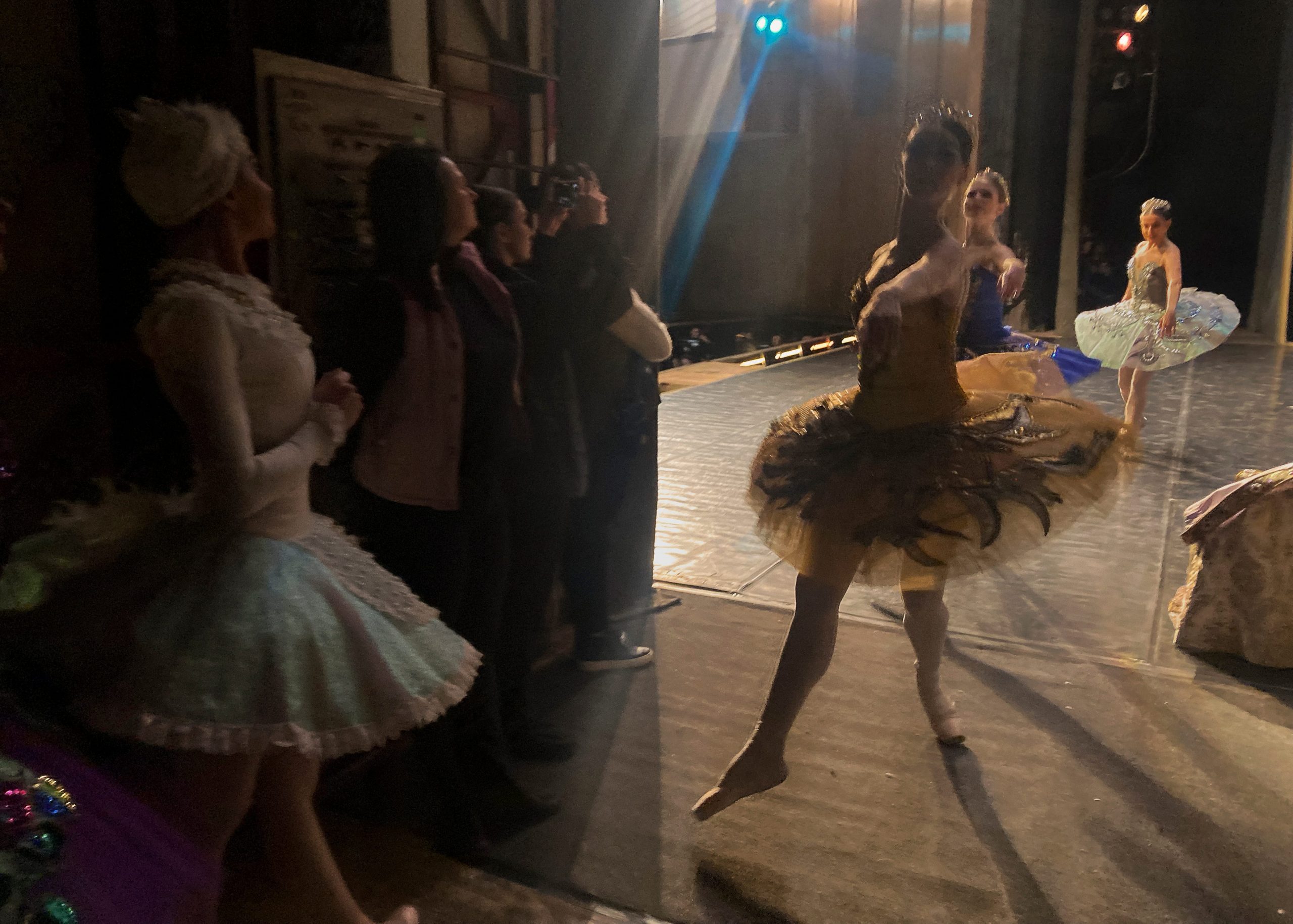 Ballet dancers are seen from backstage.