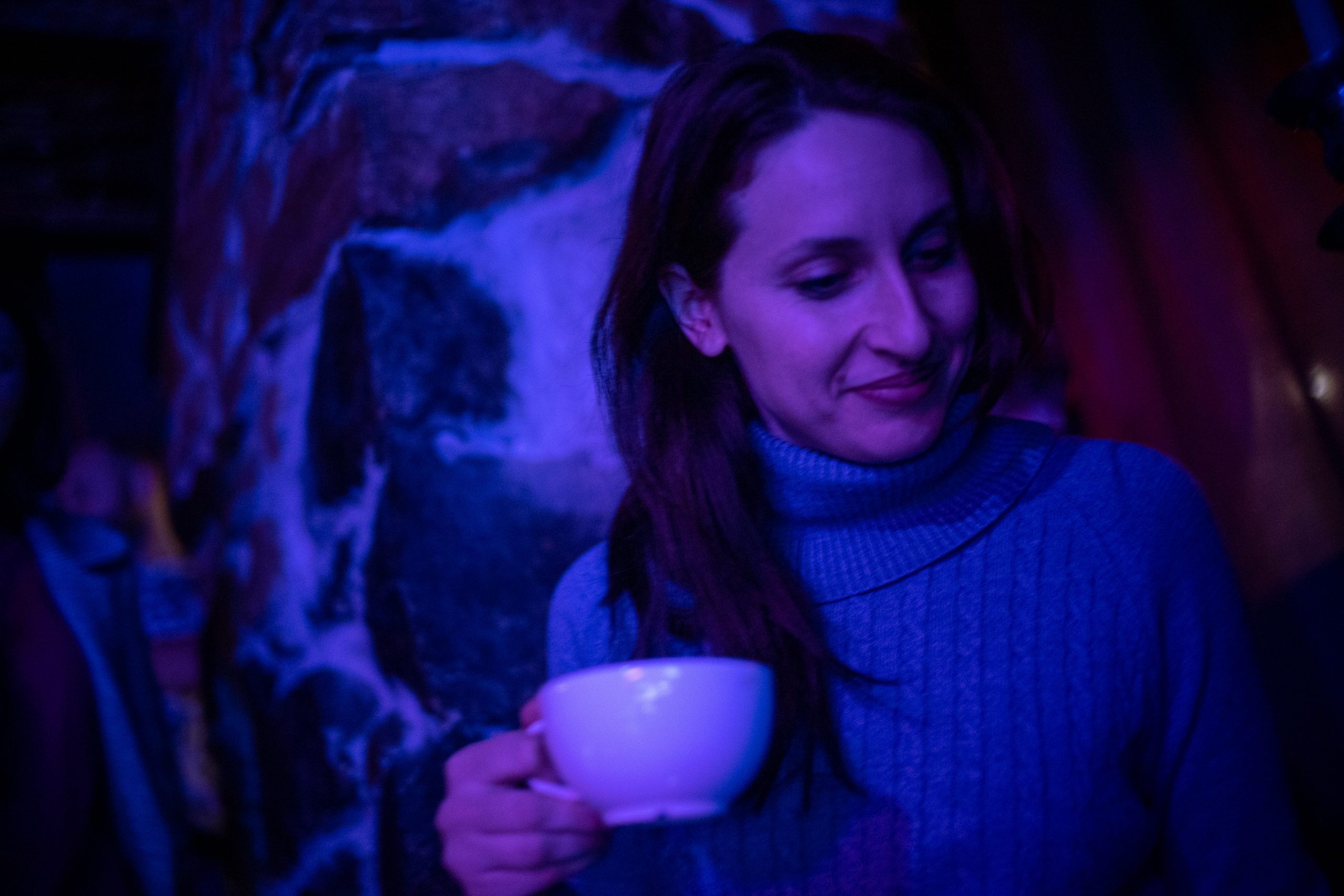 A woman glances down as she holds a teacup in one hand.