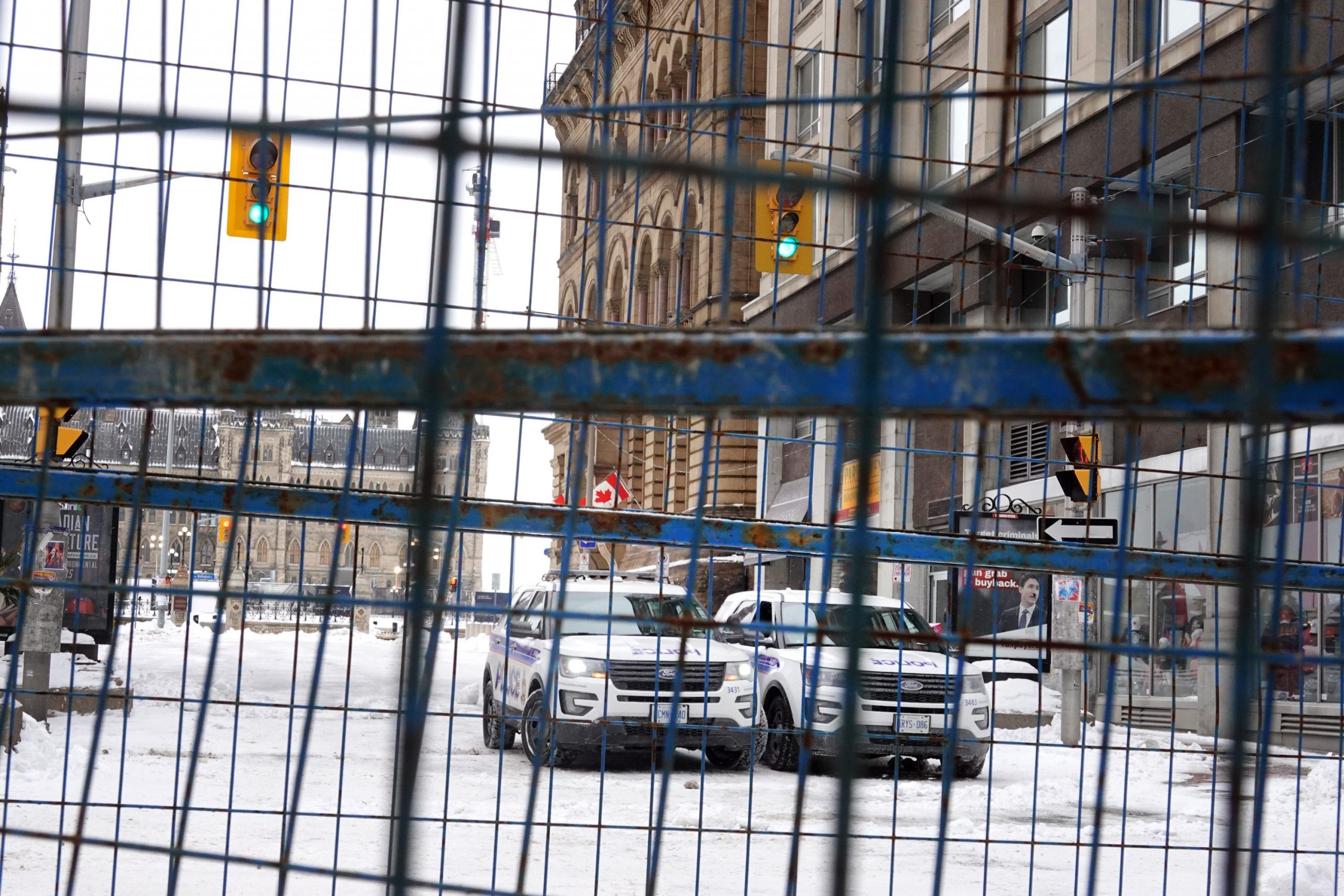 Two police vehicles parked in the snow behind a fence in Downtown Ottawa