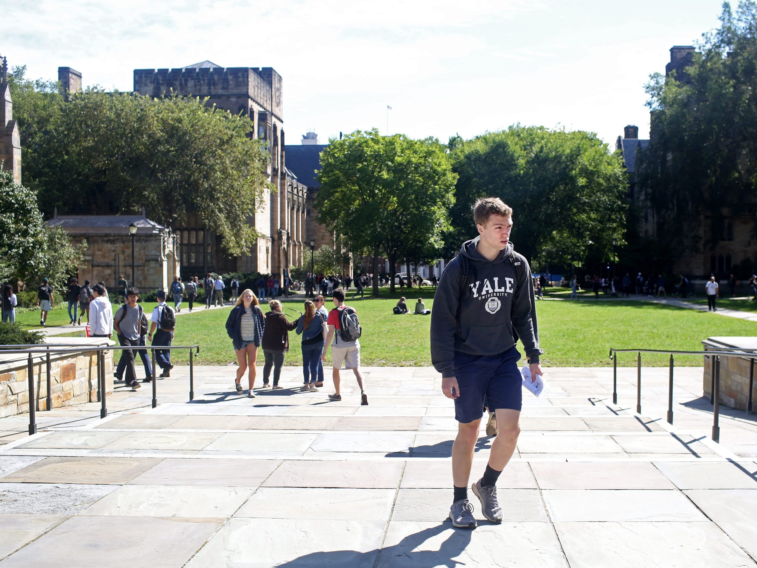 A student wearing a Yale University sweatshirt walking across campus.