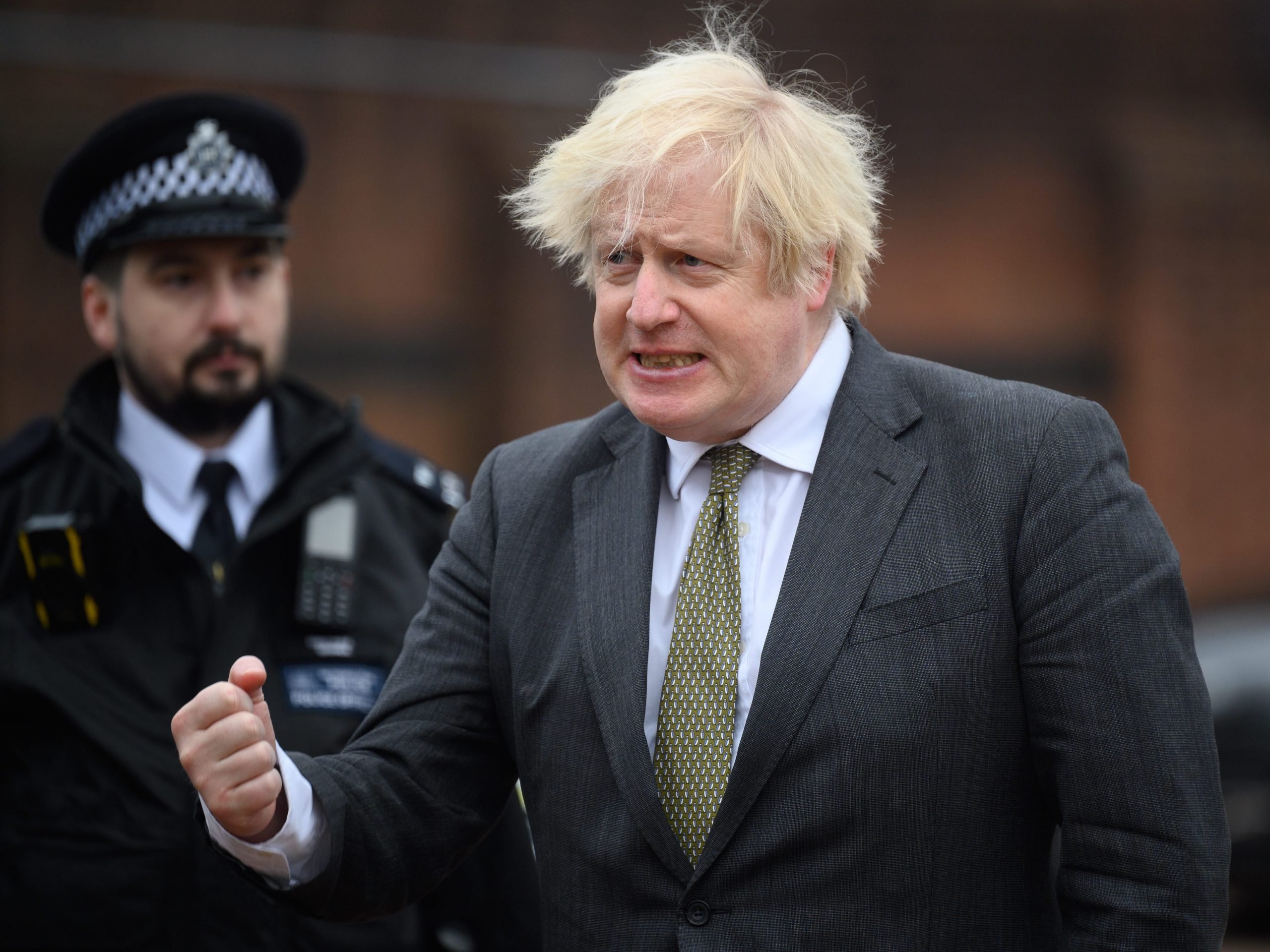 Boris Johnson at Uxbridge police station grimacing with an officer behind him