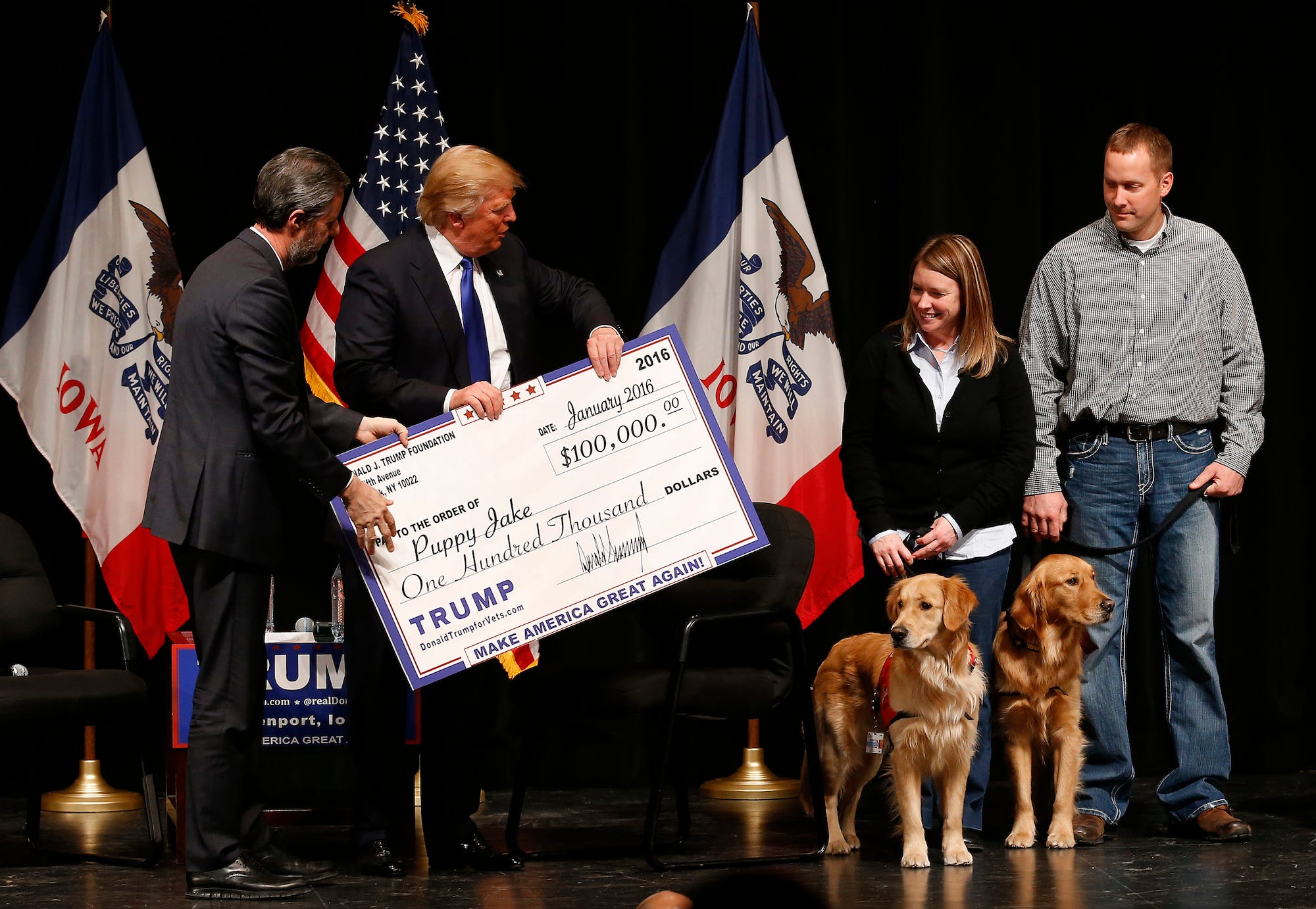 Trump presents an enlarged copy of a $100,000 check to the owners of Puppy Jake, a charity that trains dogs for veterans, at a Davenport, Iowa event on January 30, 2016.