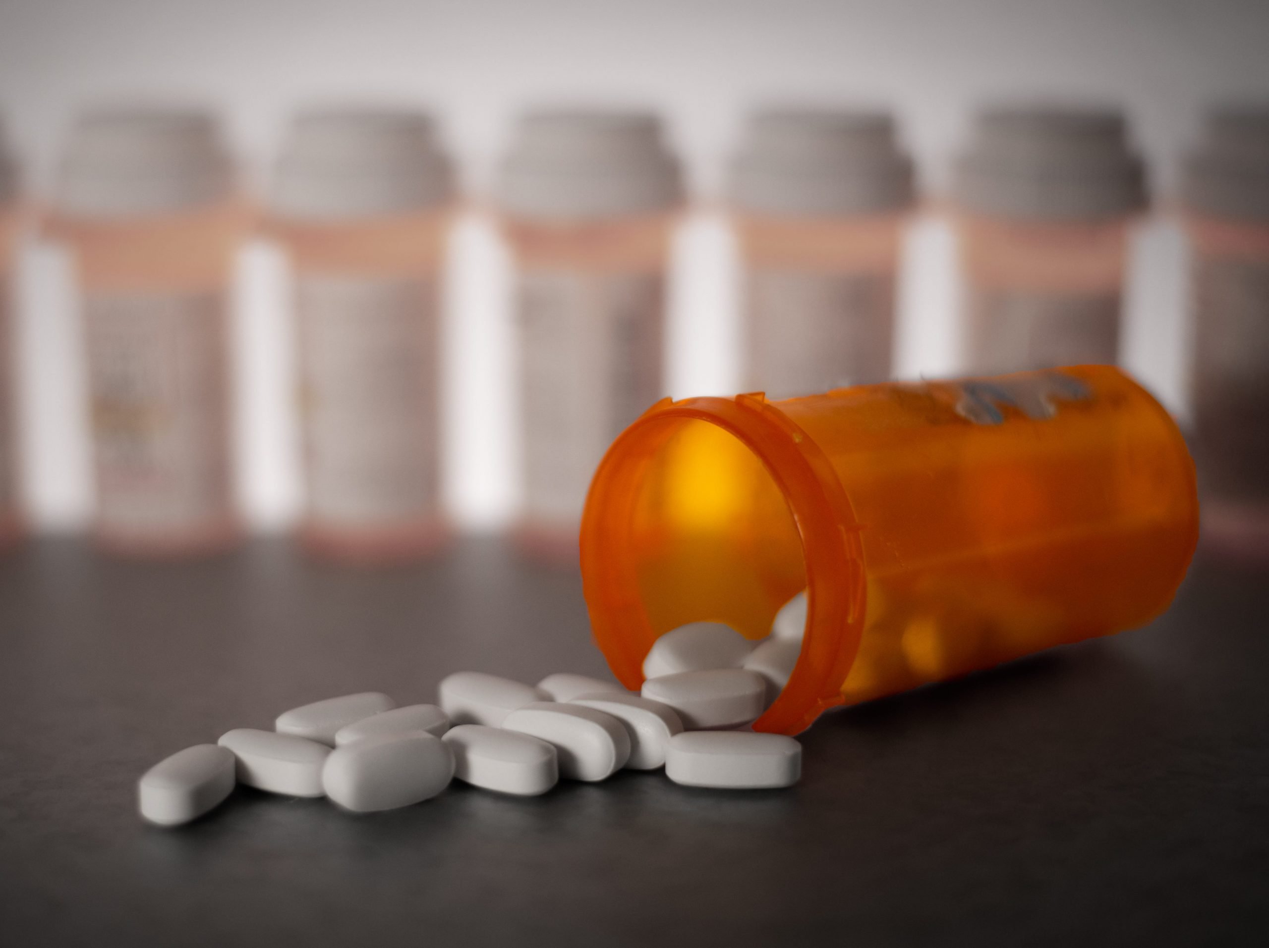 A staged photo showing pills spilling out of an orange bottle.