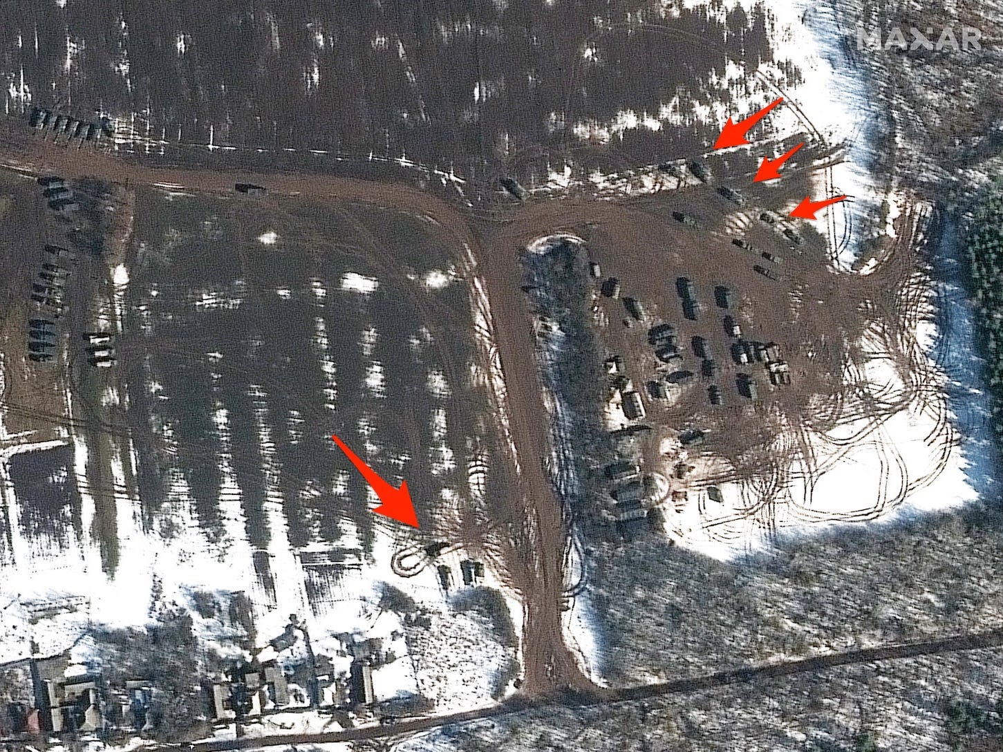 Satellite imagery of troops on the Ukrainian border with arrows pointing to vehicles and tire marks.