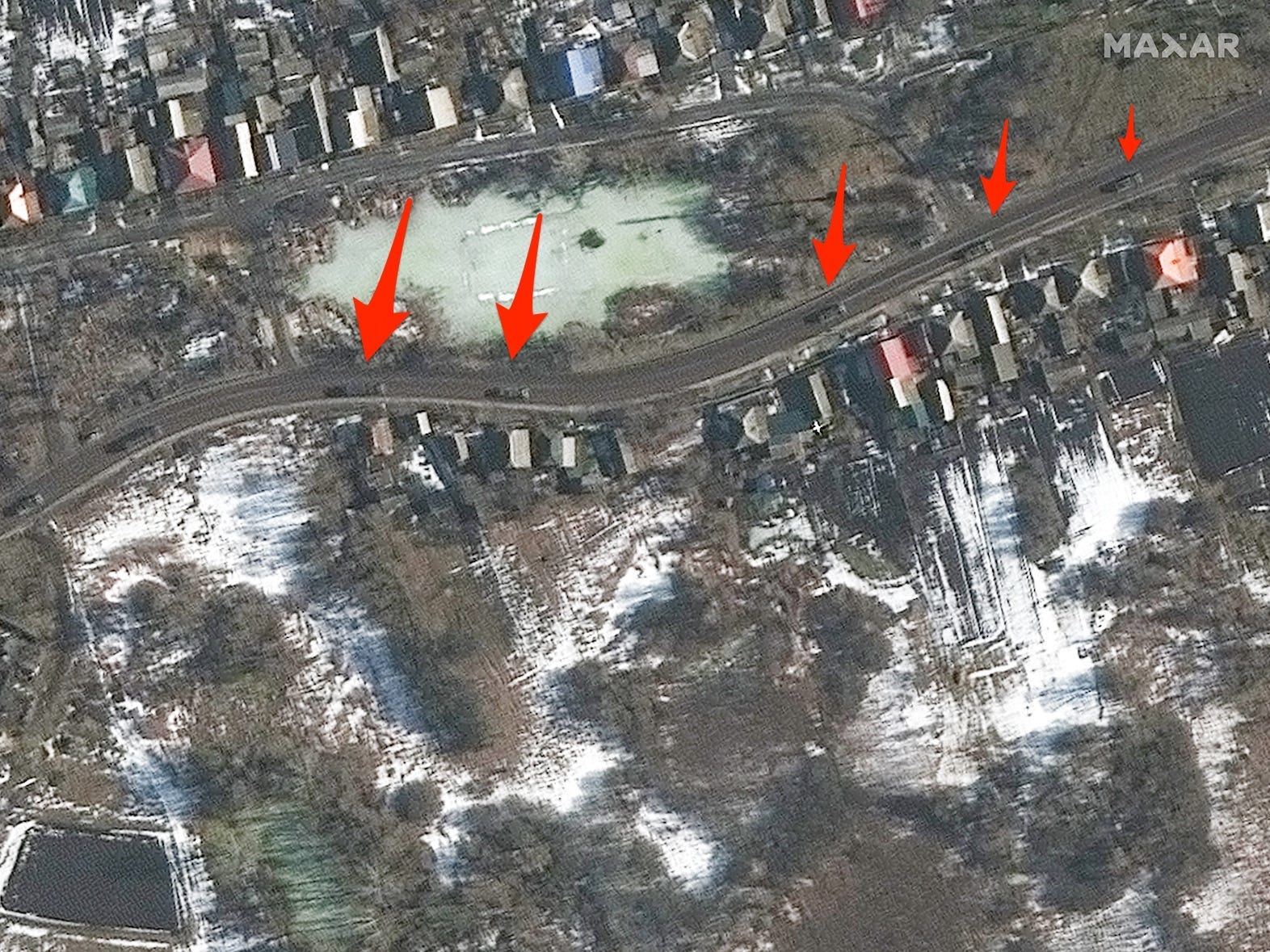 A satellite image shows vehicles on a road among houses with arrows pointing to the vehicles.
