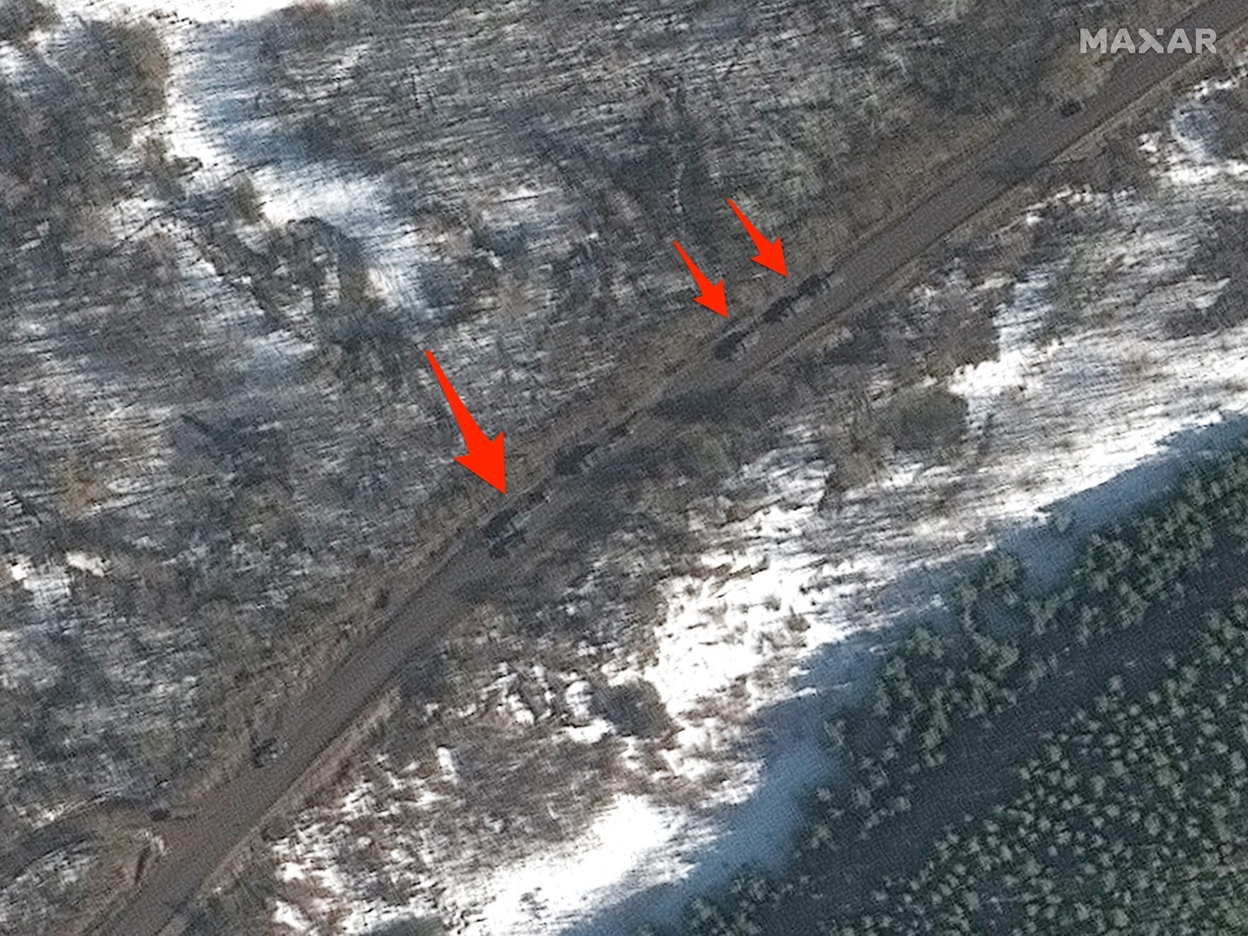 military vehicles are show on a road among a snowy forest as seen in a satellite image