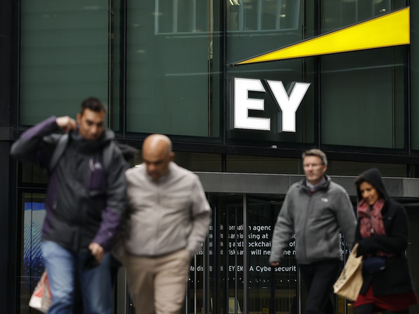 Pedestrians walk in front of the entrance to EY's head office in London.