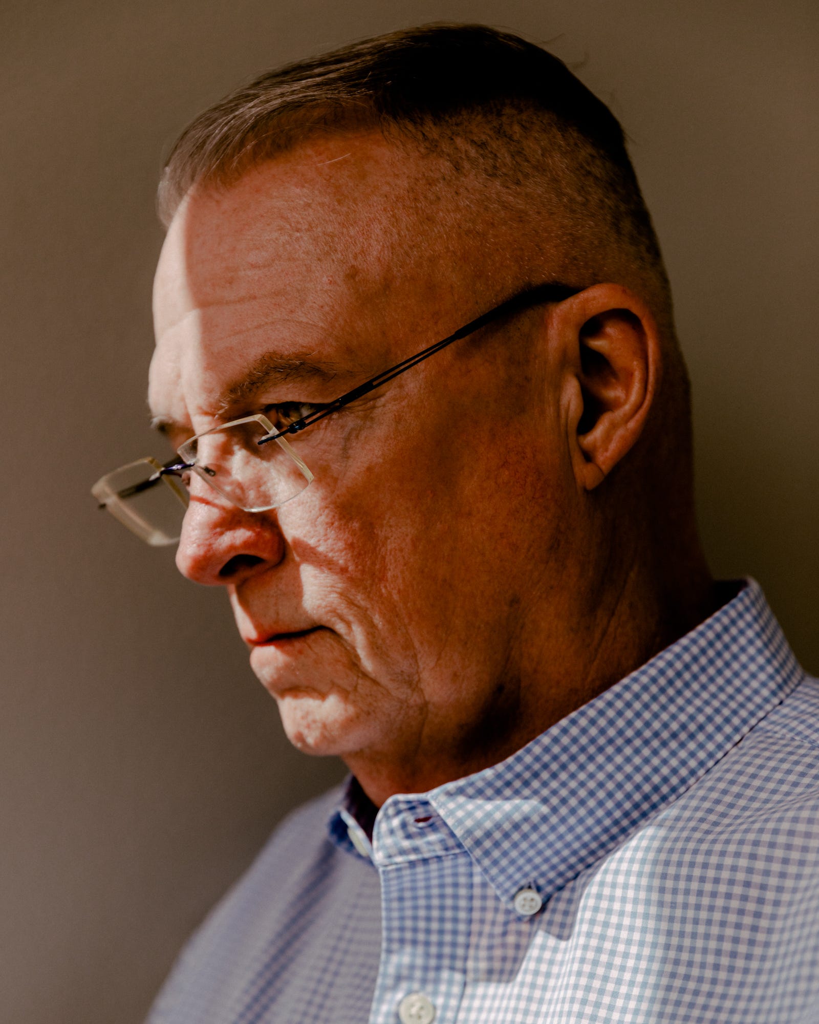 Michael Widenhoefter-Wilder, wearing glasses, stands in a sliver of sunlight.