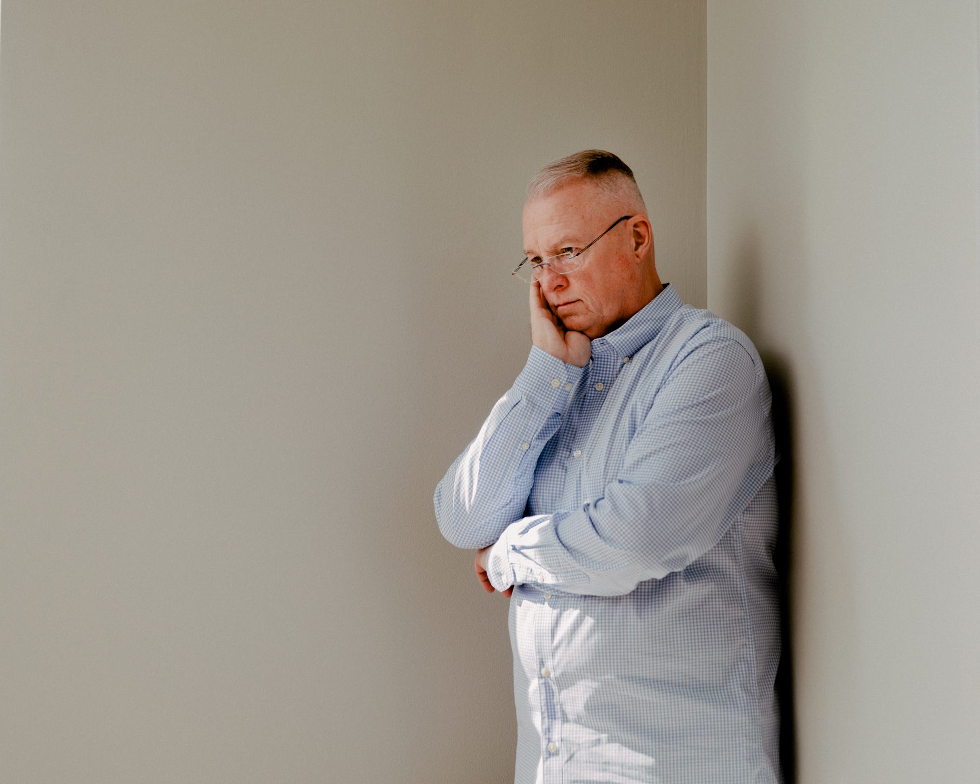 Michael Widenhoefter-Wilder stands in the corner of a room with his head resting in his hand.