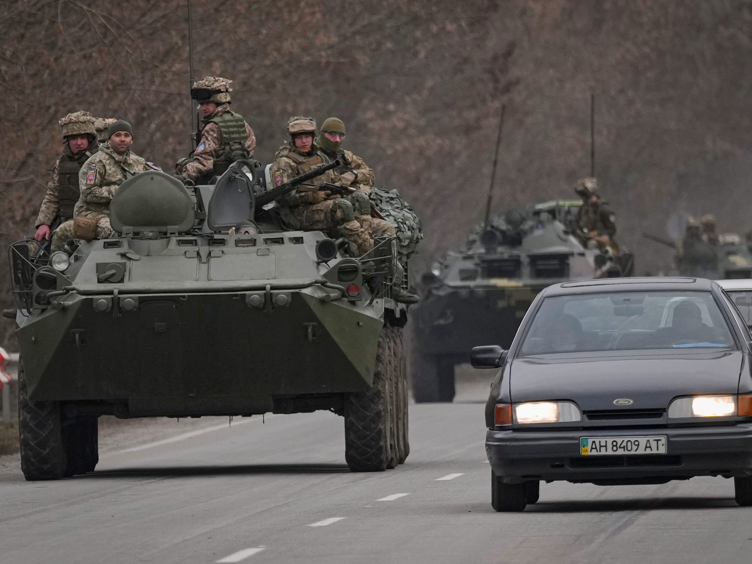 Ukrainian servicemen sit atop armored personnel carriers driving on a road in the Donetsk region, eastern Ukraine, Thursday, Feb. 24, 2022. )