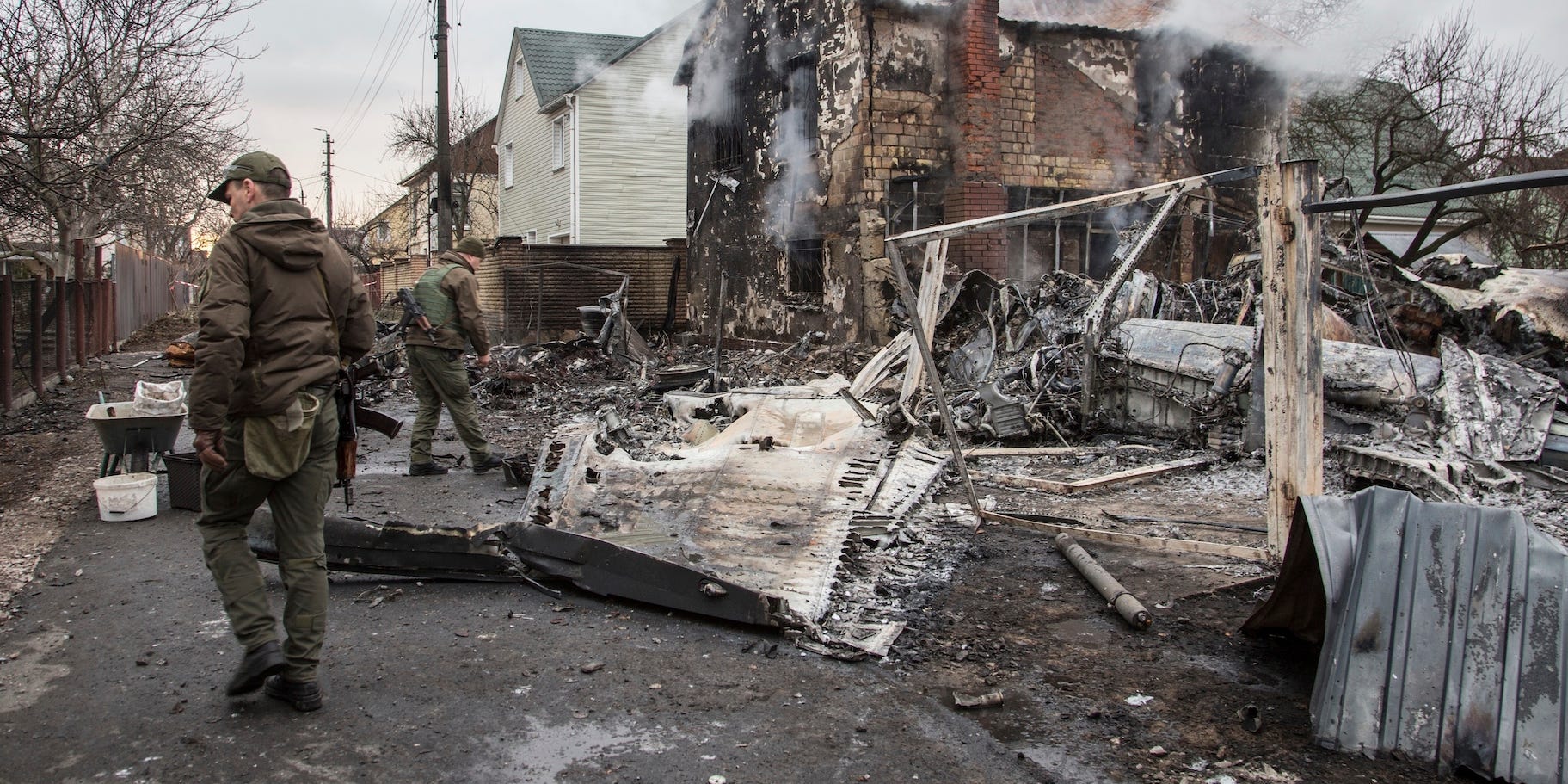 Ukrainian servicemen walk at fragments of a downed aircraft seen in in Kyiv, Ukraine, Friday, Feb. 25, 2022