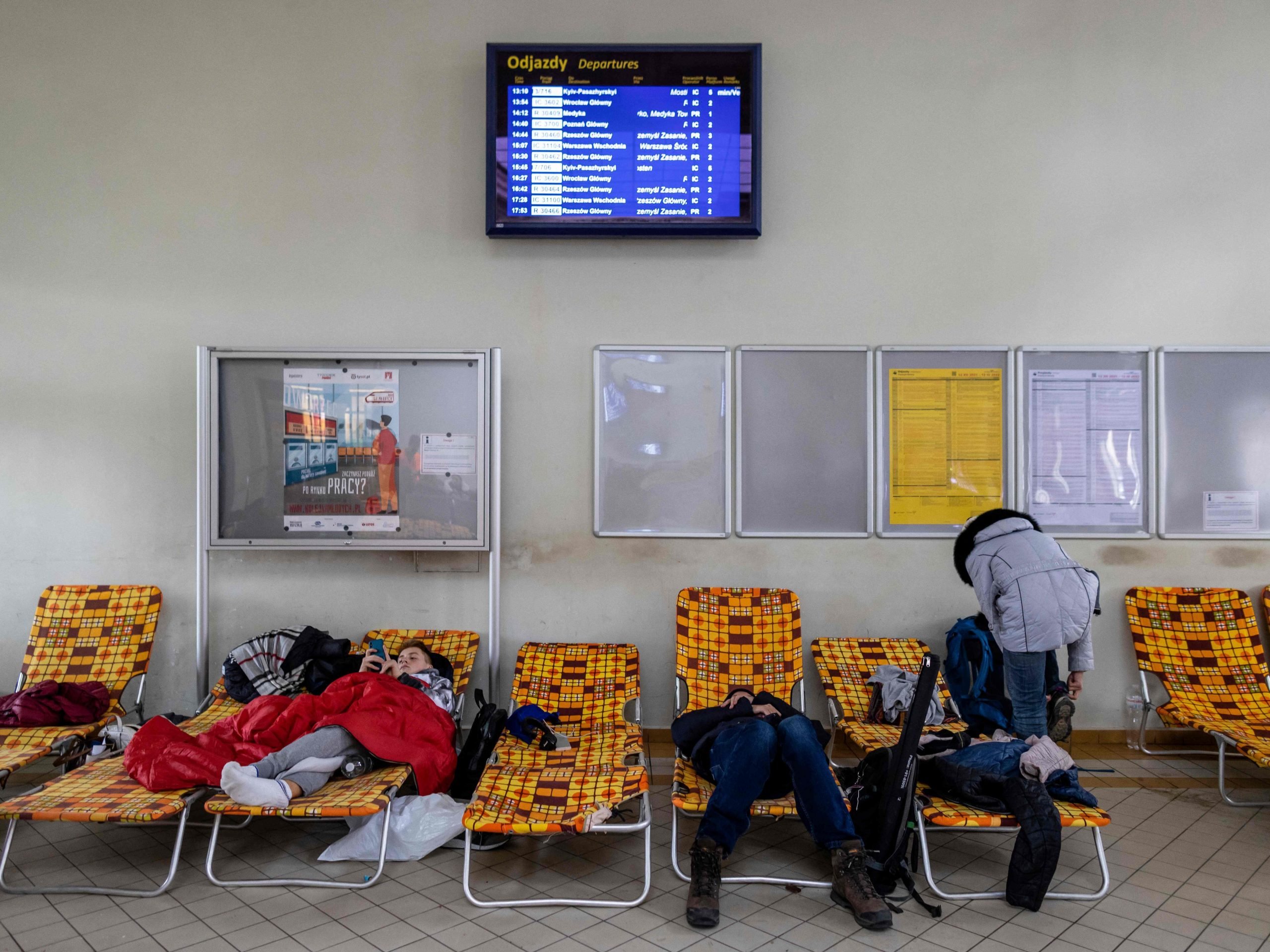 Ukrainian citizens are seen resting in the building of the main railway station of Przemysl which has been turned into a temporary reception centre for refugees from Ukraine fleeing the conflict in their country, in eastern Poland on February 25, 2022, one day after Russia launched a military attack on its neighbour Ukraine.