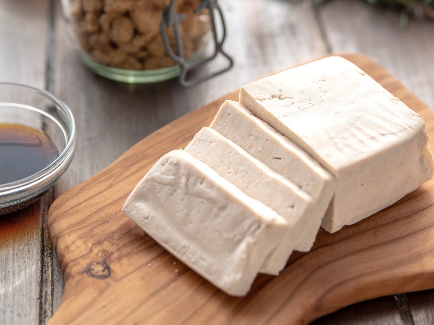 Tofu sliced on a cutting board with styling in the background