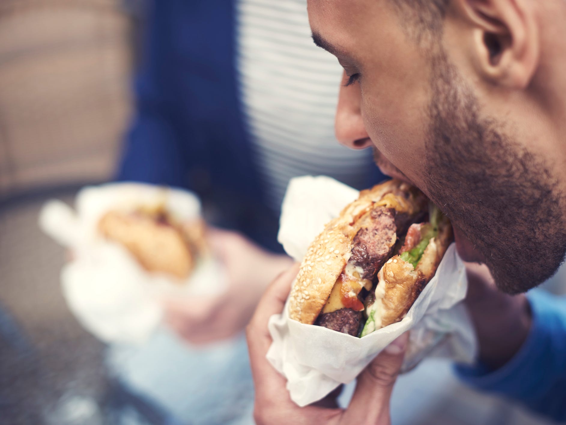 a close-up of a man eating a cheeseburger