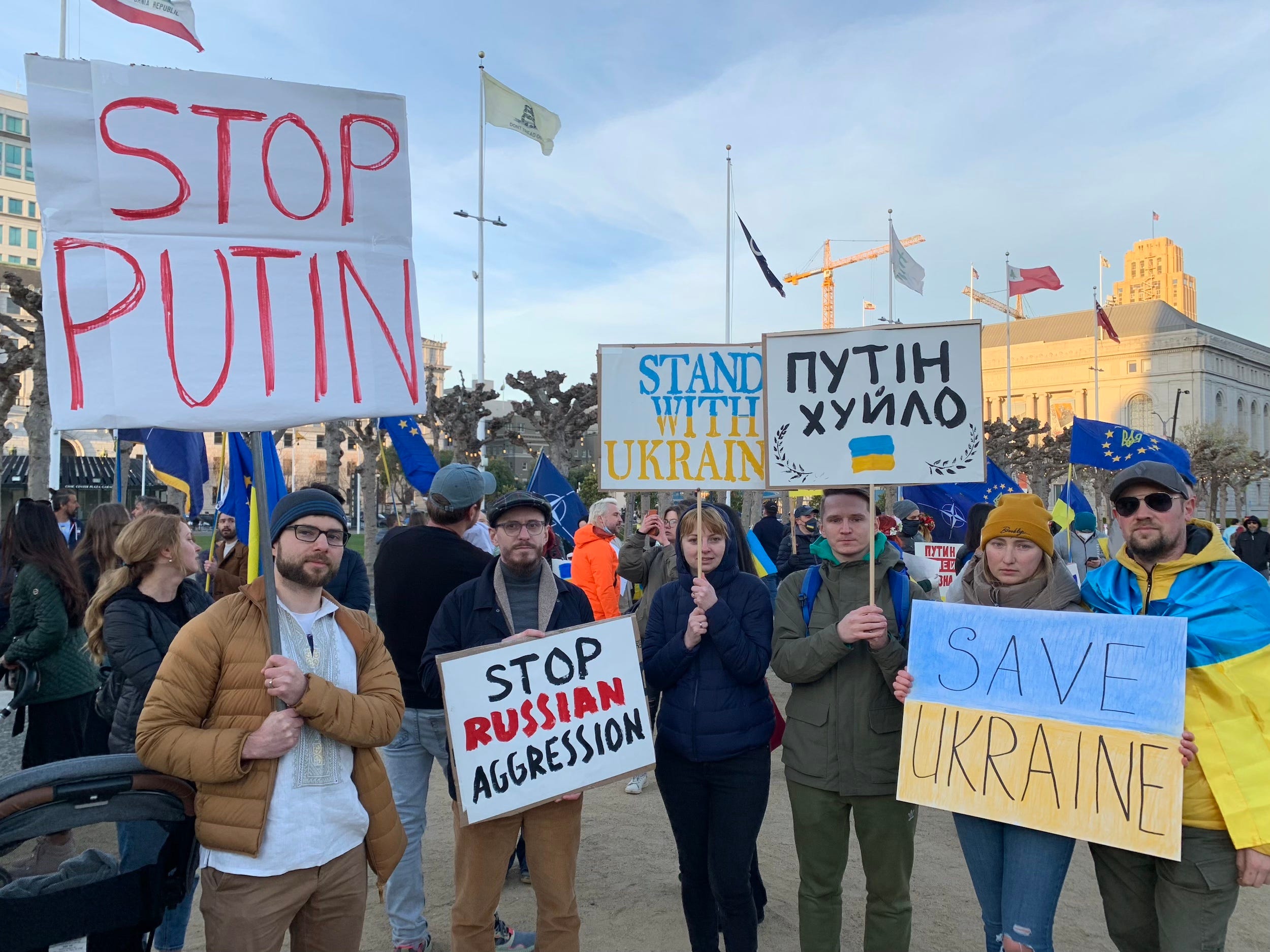 six protestors pose with signs that read "stop putin" "stand with ukraine" "stop russian aggression" and "save ukraine"