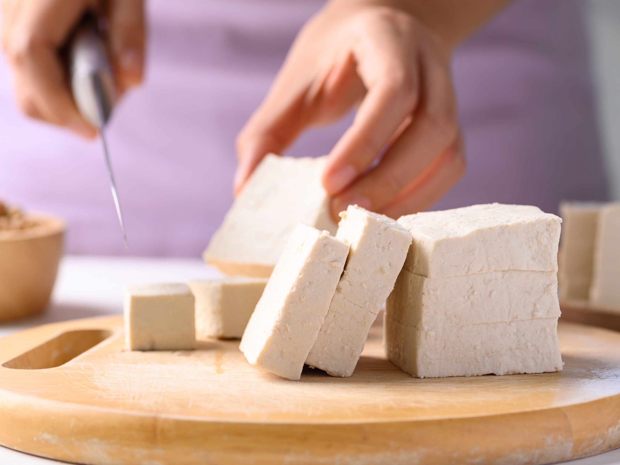 Person cutting tofu on a cutting board