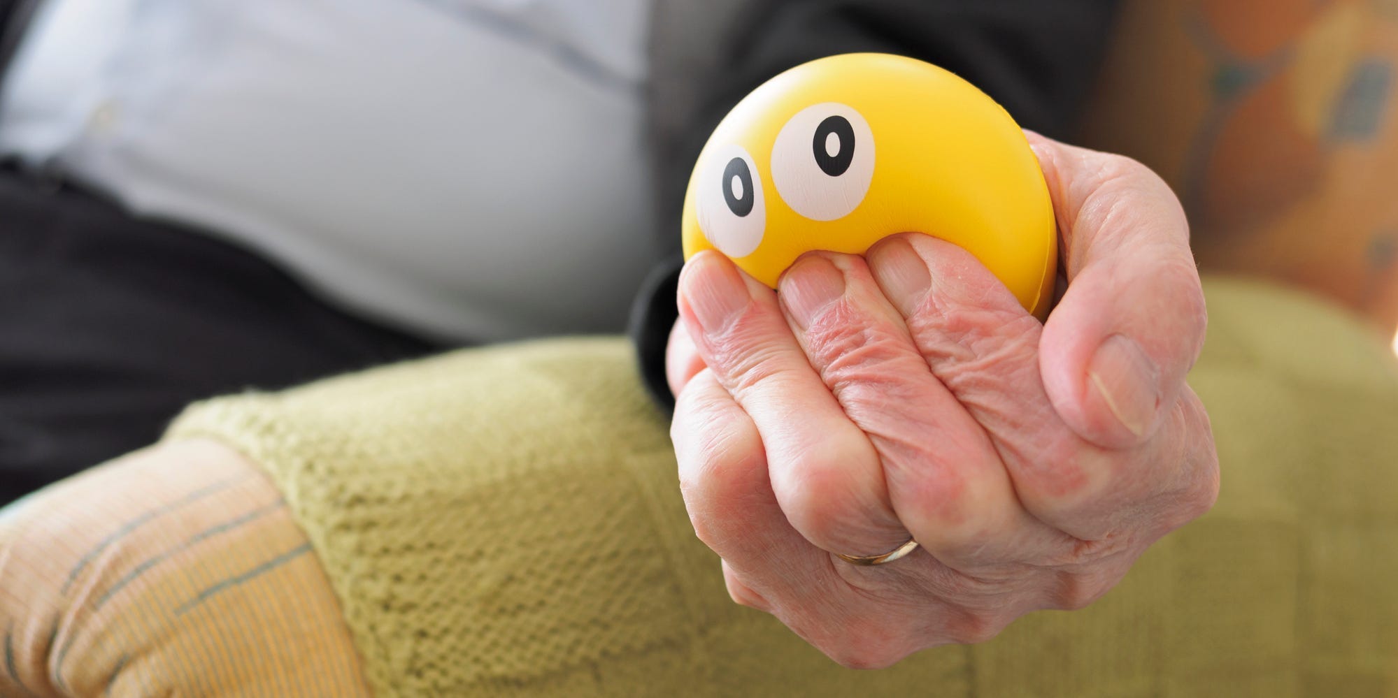 A person squeezes a yellow stress ball.