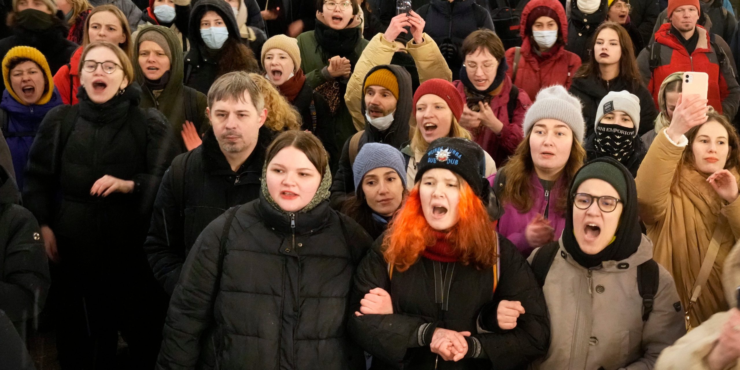 Dozens of demonstrators hold arms and shout slogans.