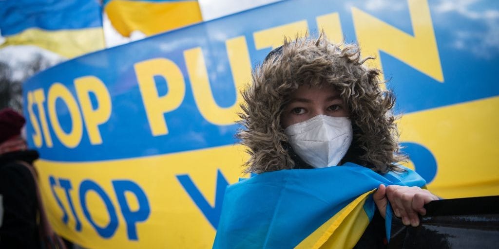 A protester stands in front of a banner reading "Stop Putin - Stop War" during a demonstration for peace in Ukraine in front of the Brandenburger Gate in Berlin