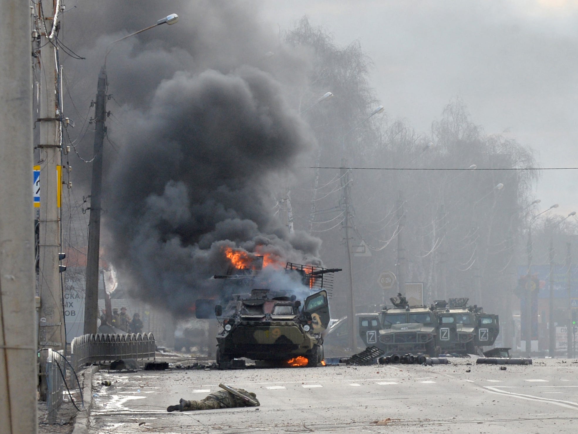 This photograph taken on February 27, 2022 shows a Russian Armoured personnel carrier (APC) burning next to unidentified soldier's body during fight with the Ukrainian armed forces in Kharkiv.