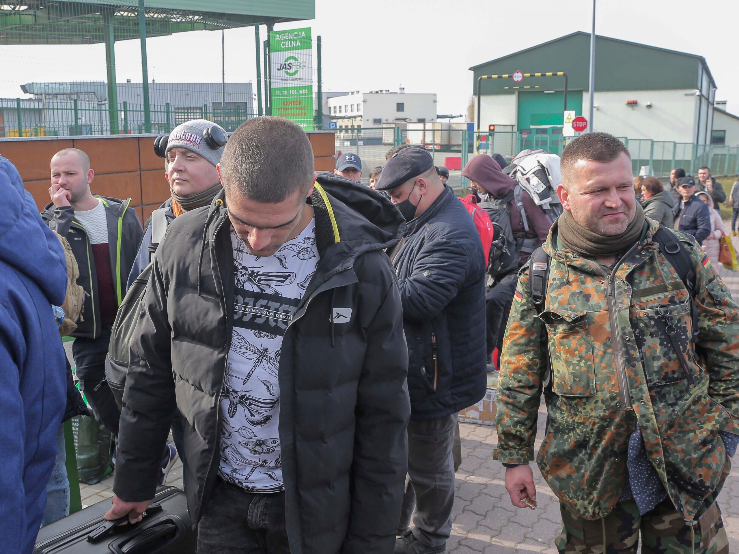 men in military uniform wait in line in Poland