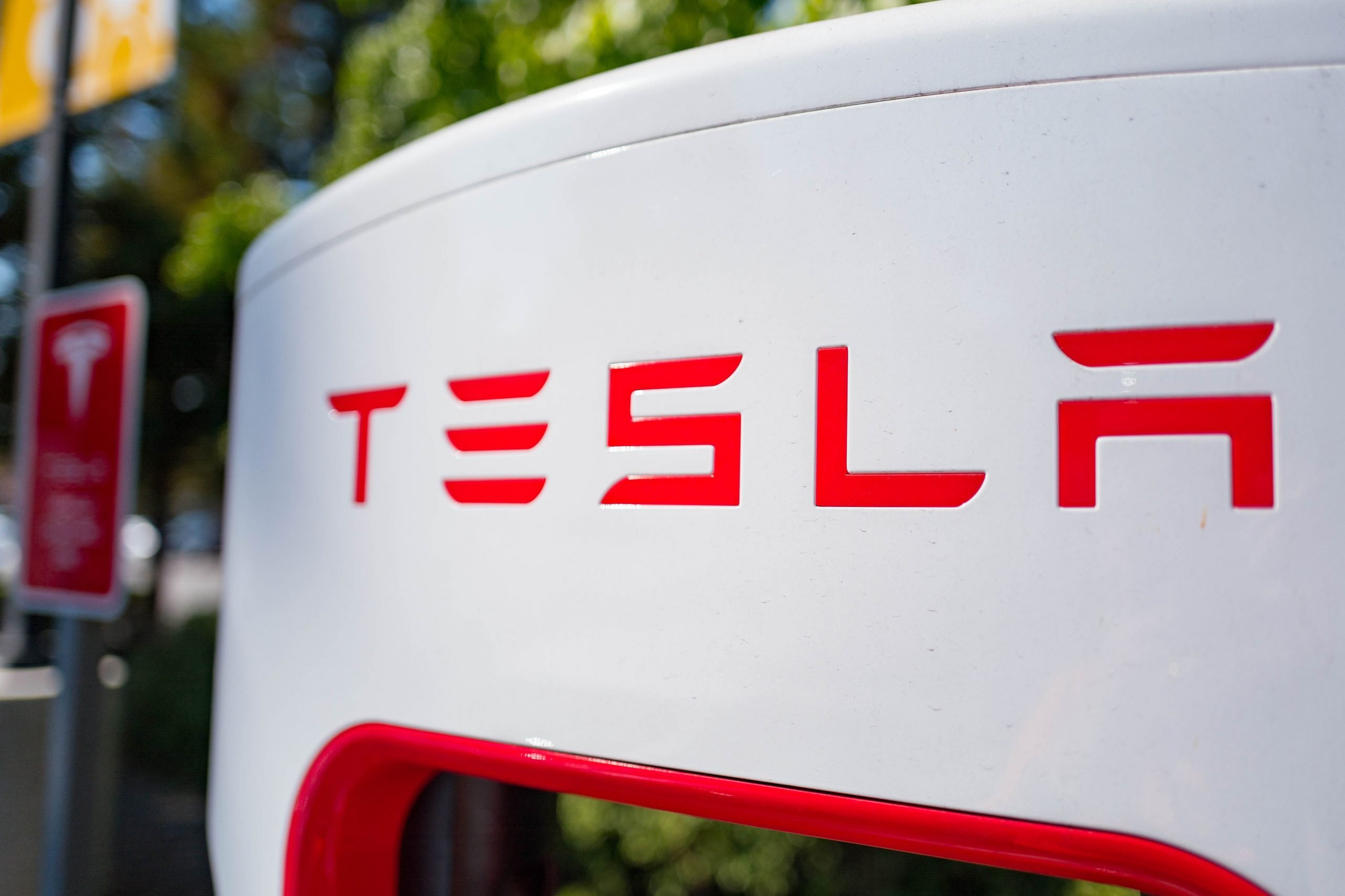 A close-up red Tesla logo on a white background.