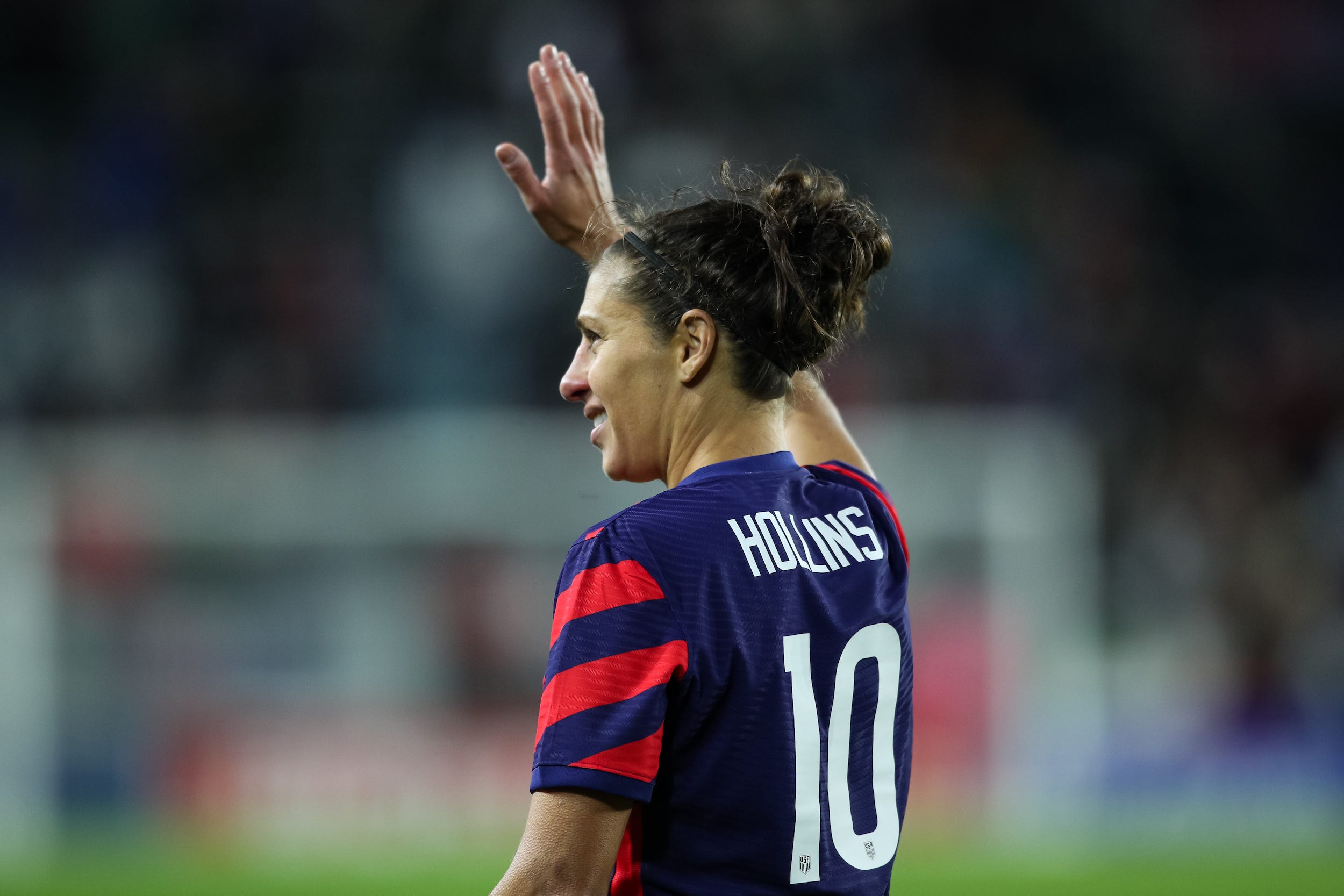 Carli Lloyd, wearing a jersey with her husband's surname on the back, waves to fans after her final game as a member of the US Women's National Team
