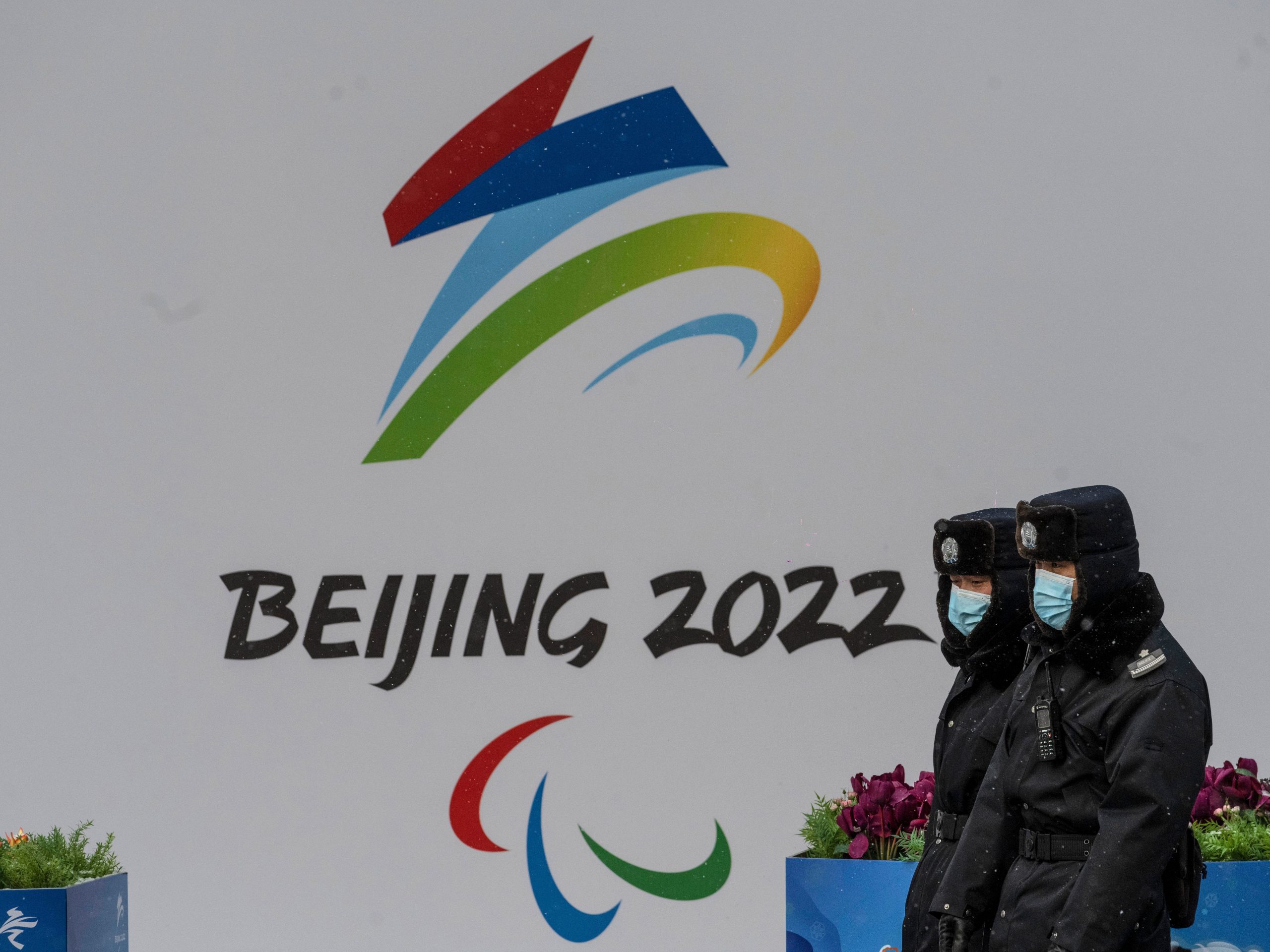 Security walk by a billboard for the Beijing 2022 Winter Olympics and Paralympics during a snowfall on January 20, 2022 in Beijing, China.