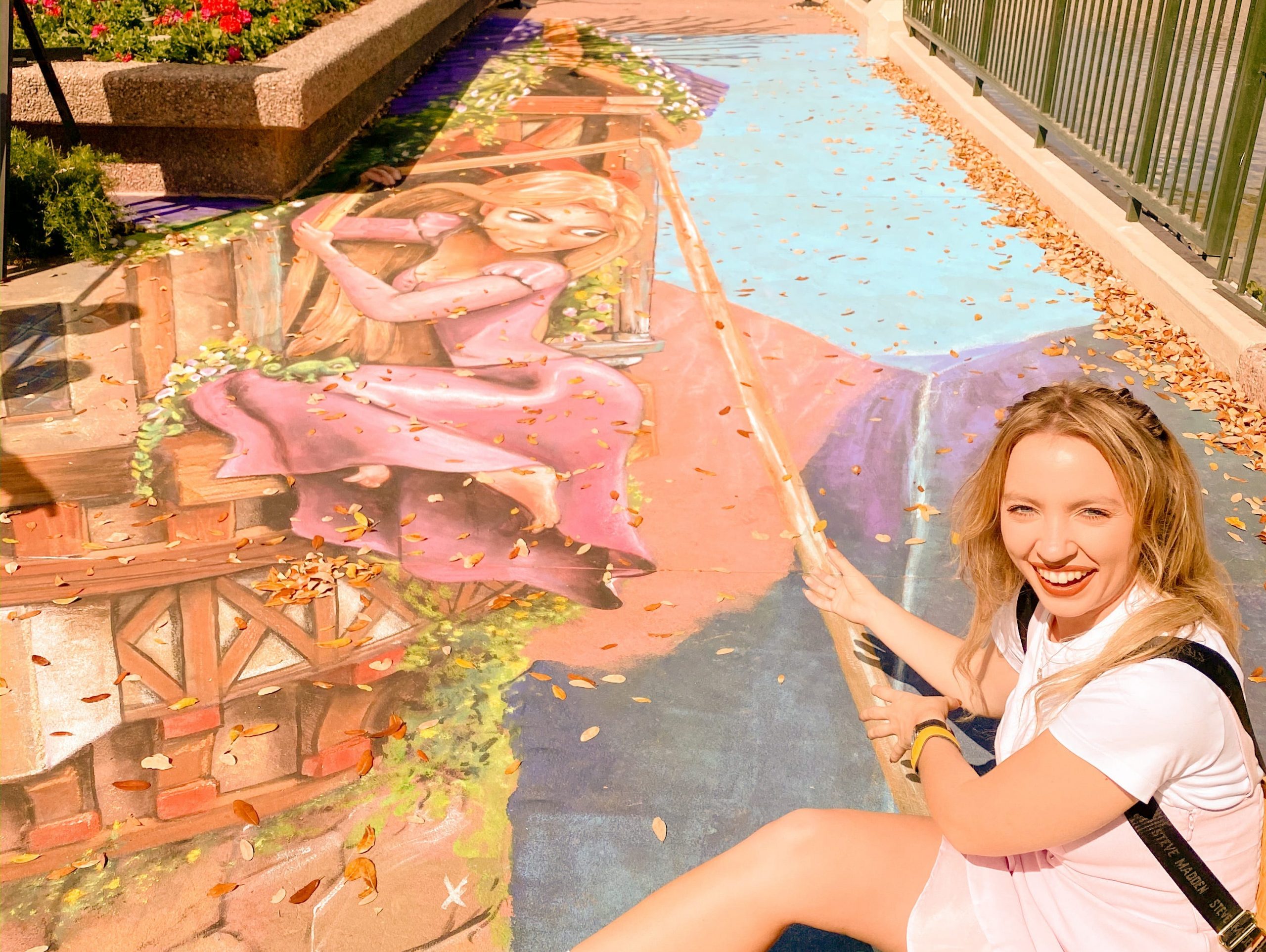kayleigh posing next to a rapunzel themed chalk mural at epcot festival of the arts