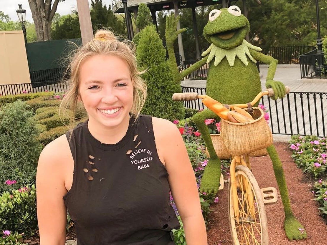 kayleigh posing next to a kermit the frog topiary at the epcot flower and garden festival