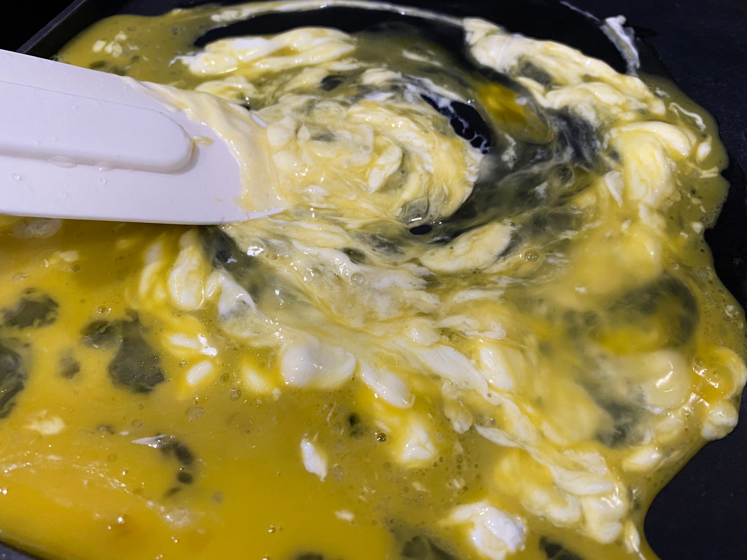 Sour cream and raw eggs stirred with a rubber spatula in pan