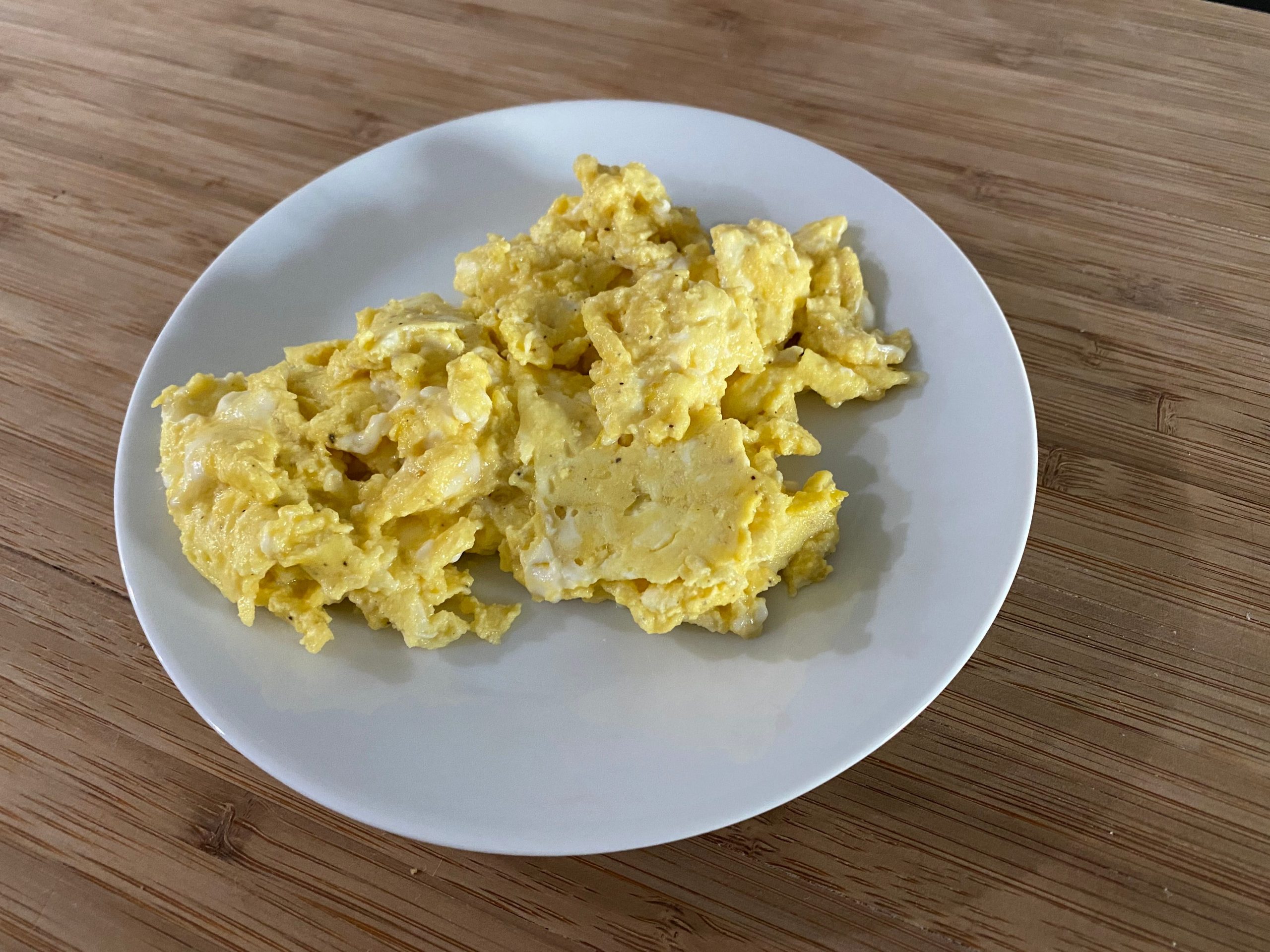 Scrambled eggs with a rubbery look on a white plate