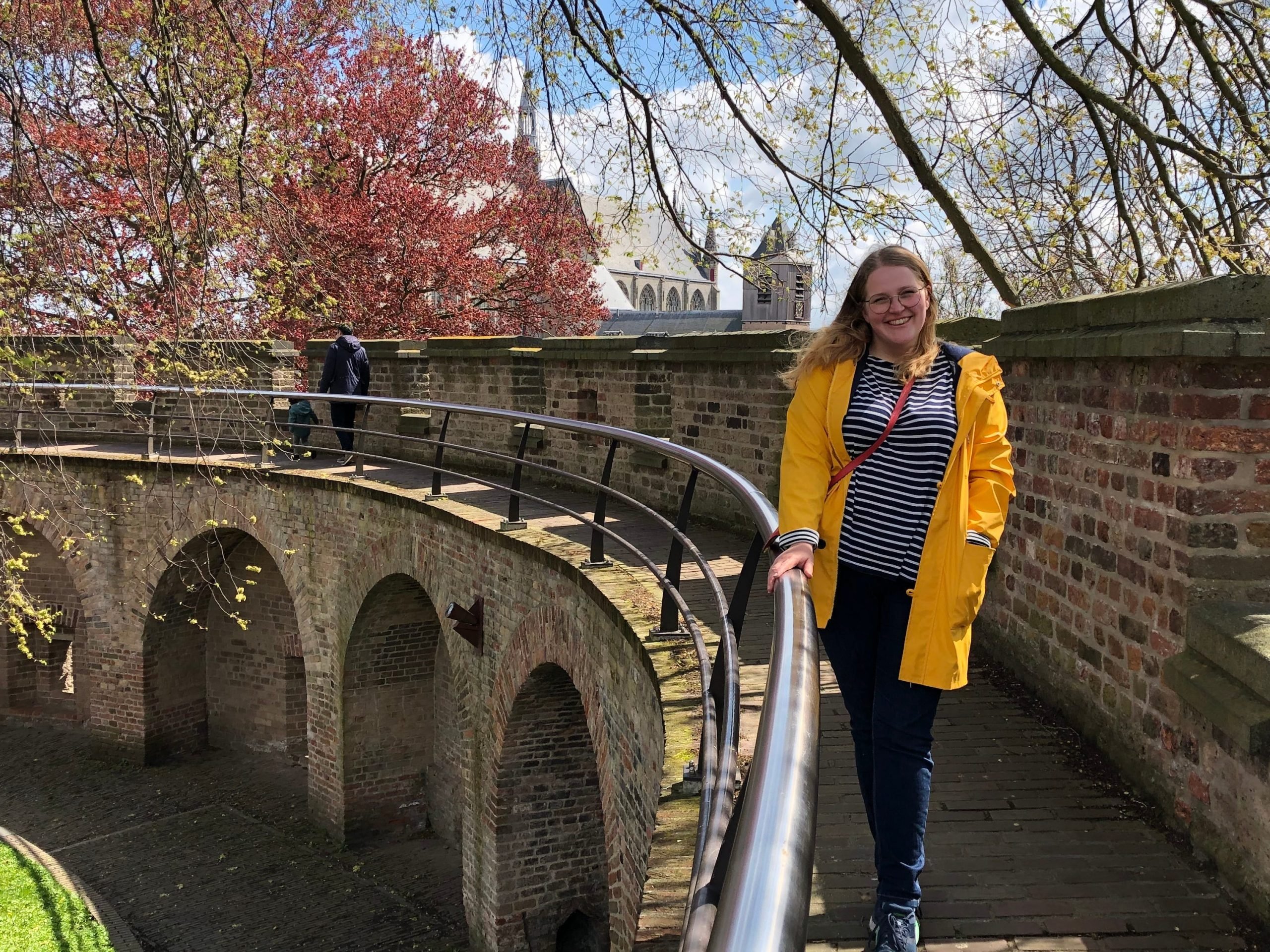 sara posing on a stone bridge next to autumnal trees in the netherlands