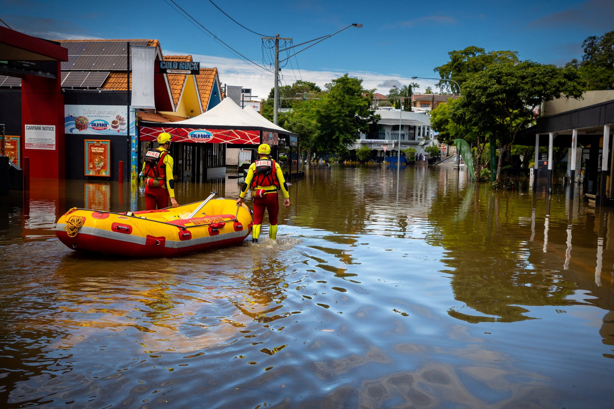 Two rescue crew members move a boat through flooded streets in Brisbane.