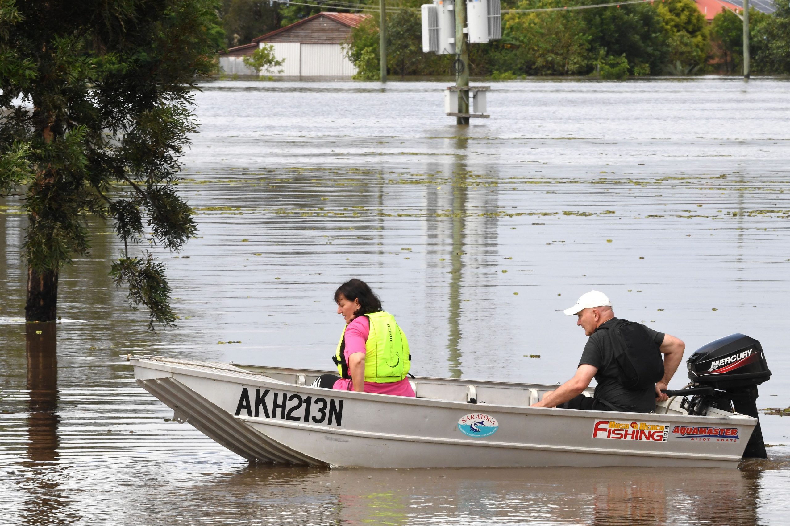 A family steers their boat through a flooded street in a residential area of Lawrence suburb, some 70 kilometres of New South Wales border city Lismore, on March 1, 2022.