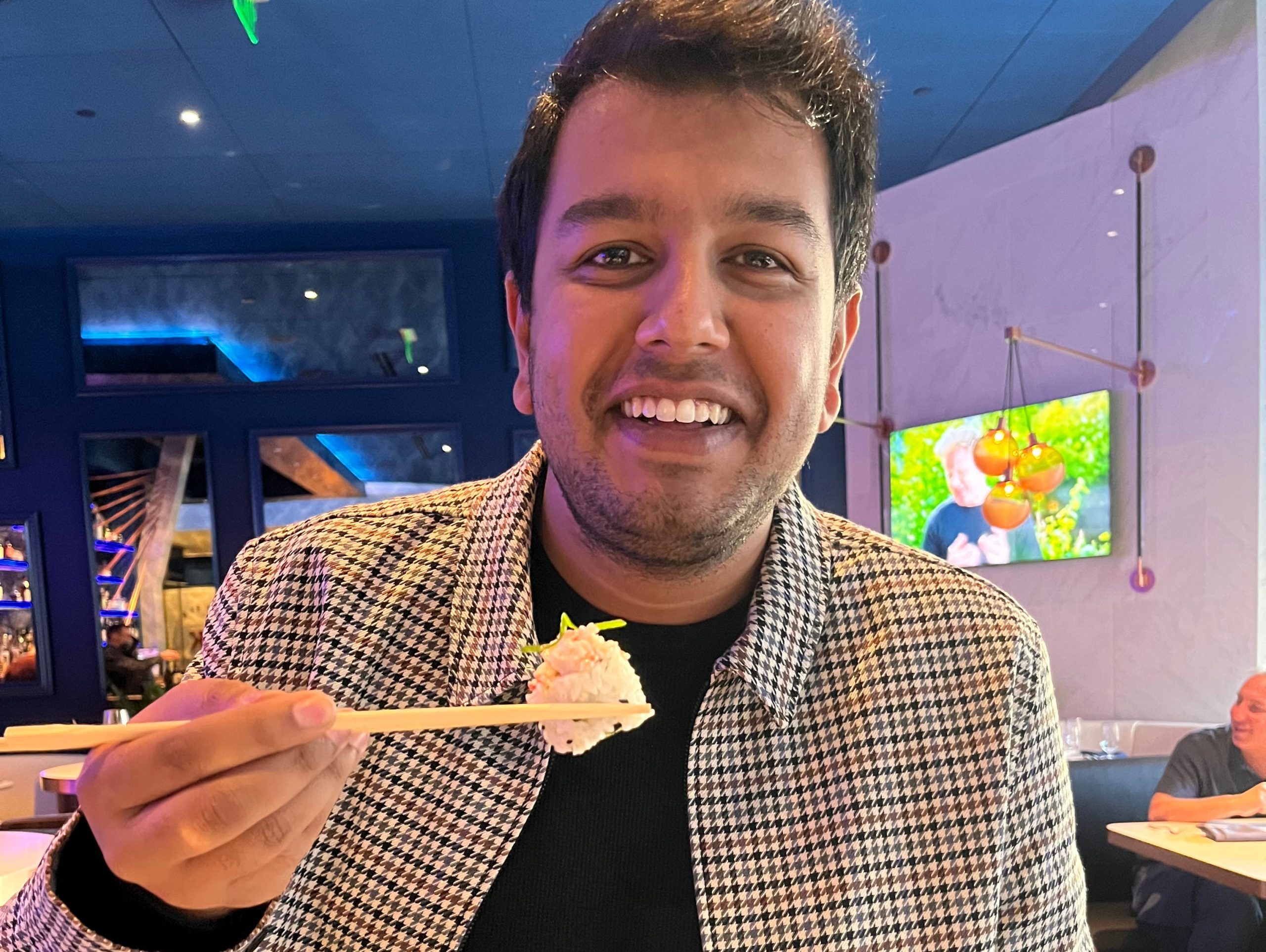 The writer holds a piece of sushi with chopsticks