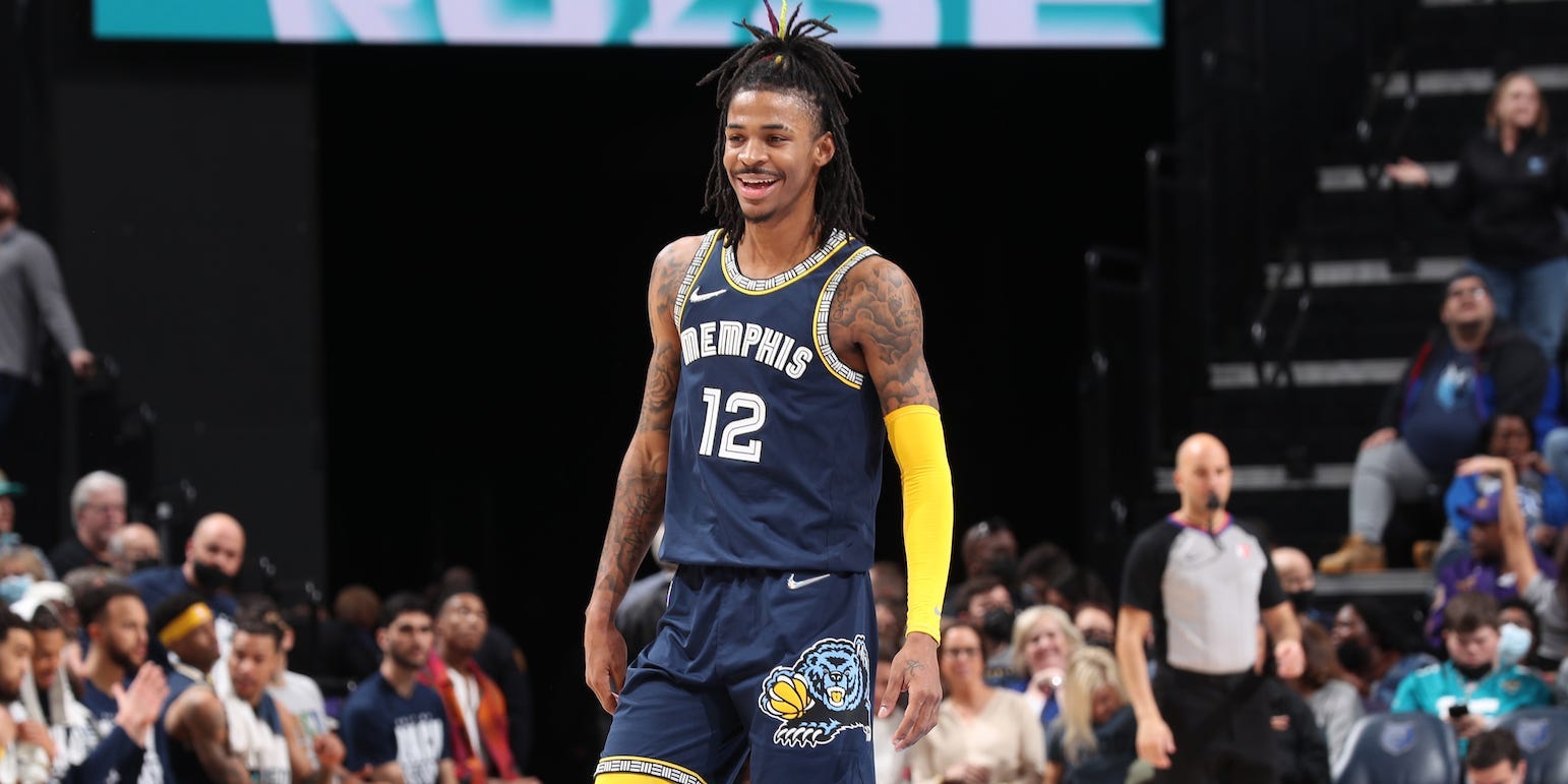 Ja Morant smiles while standing at midcourt during a game in 2022.