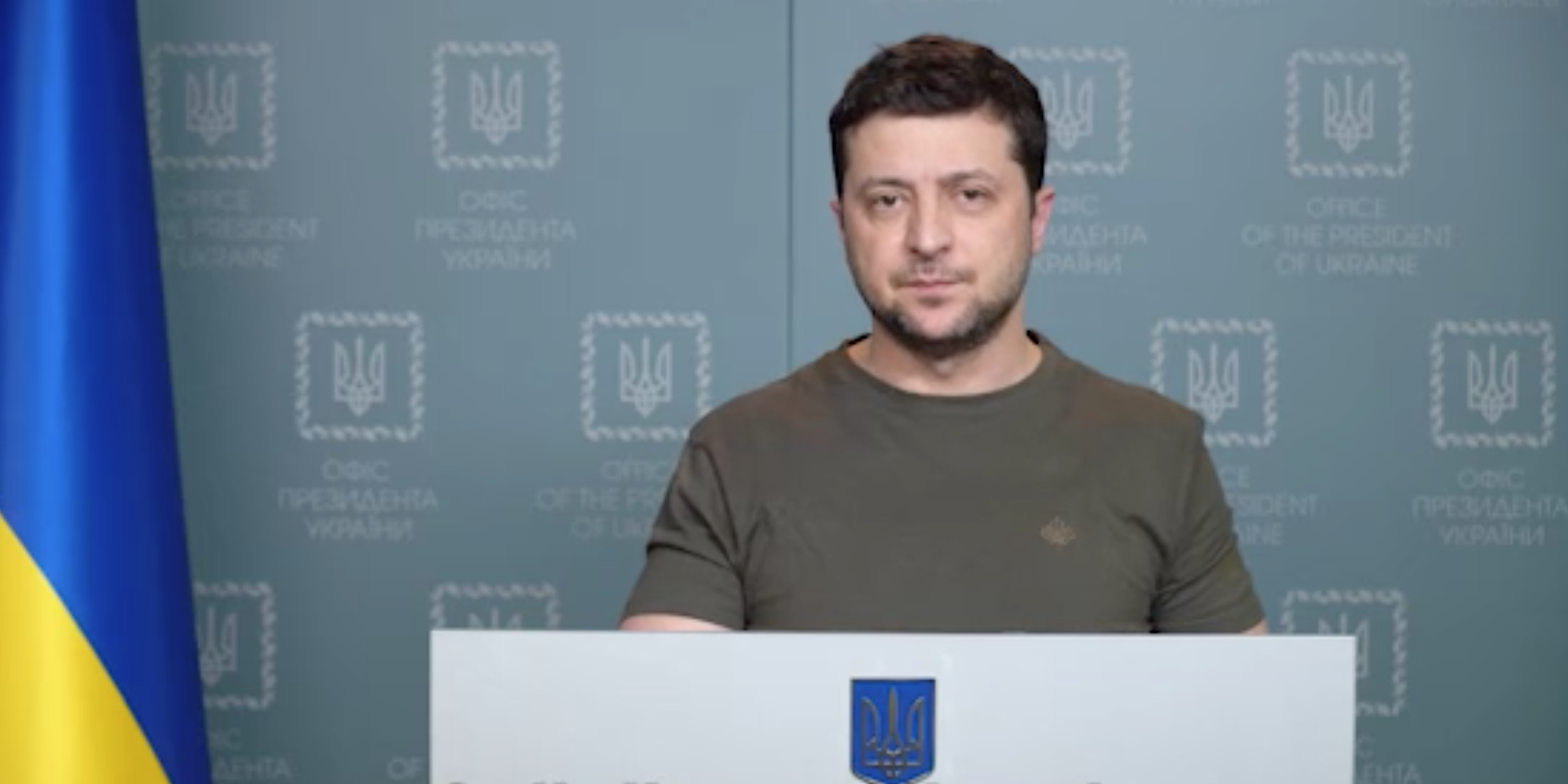 Volodymyr Zelensky speaks at a podium with Ukraine's flag behind him