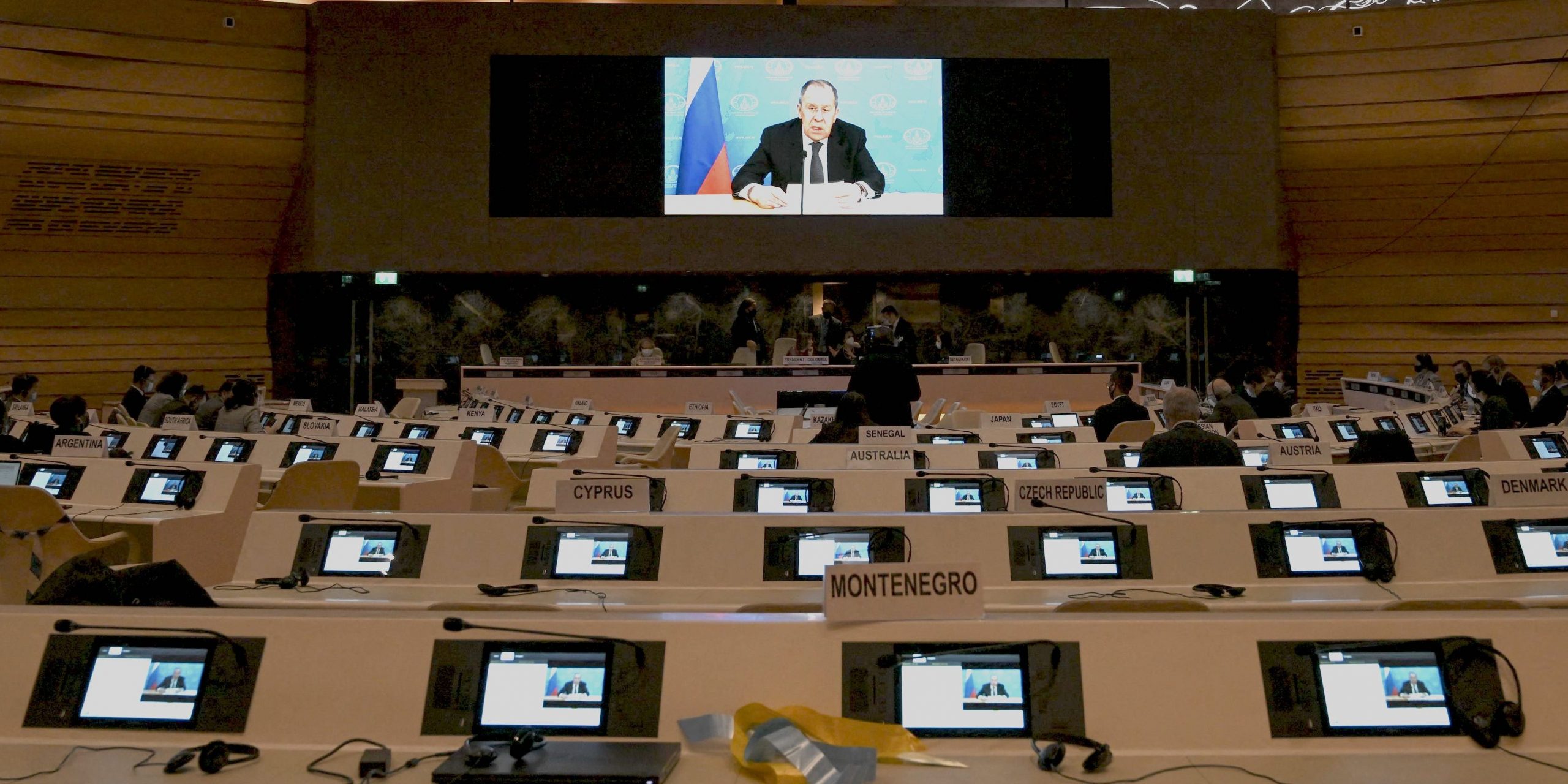 The UN Security Council meeting room appears almost empty while a Russian representative is speaking remotely on a monitor.