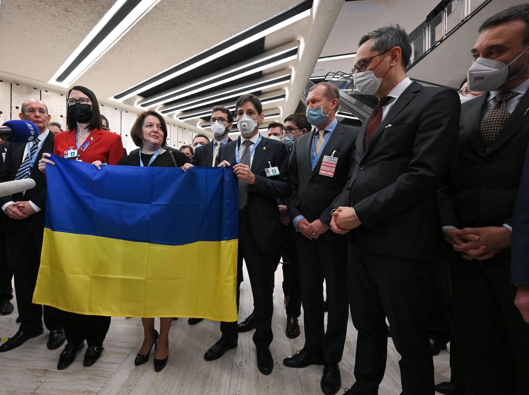 representatives gather around Ukraine's ambassador Yevheniia Filipenko holding a flag after the walkout.